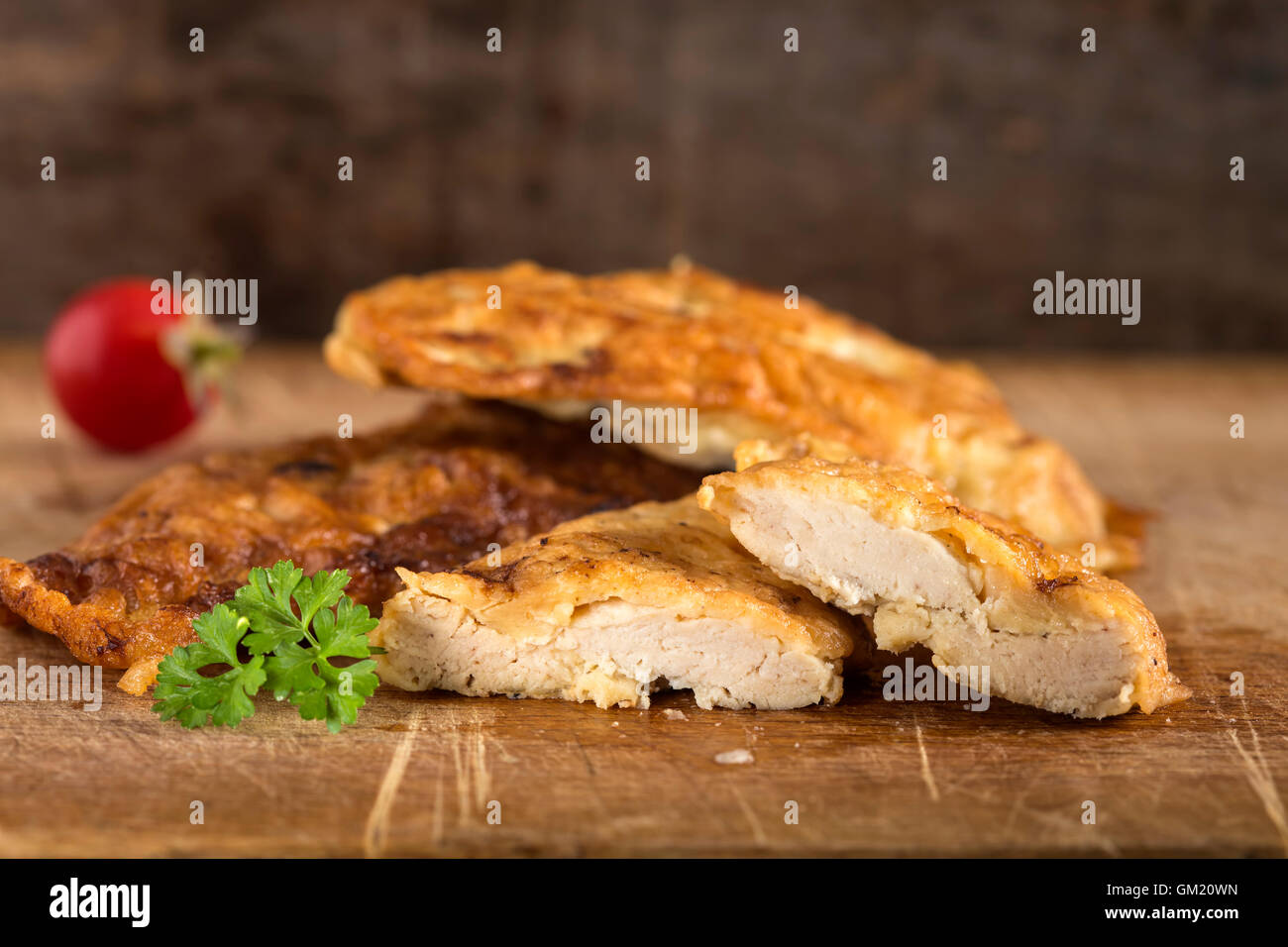 Chicken schnitzel on wood with parsley and tomato Stock Photo