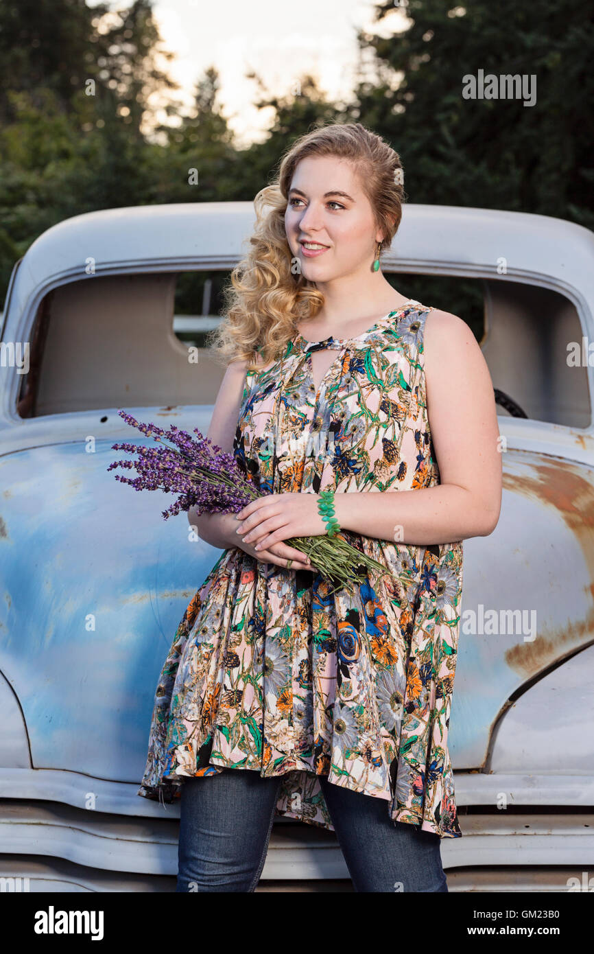 Stylish young woman posing in front of vintage farm truck at a lavender farm Stock Photo
