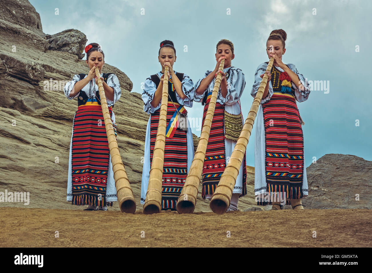 Bucegi Mountains, Romania - August 6, 2016: Group of Romanian female tulnic players dressed in colorful traditional costumes Stock Photo