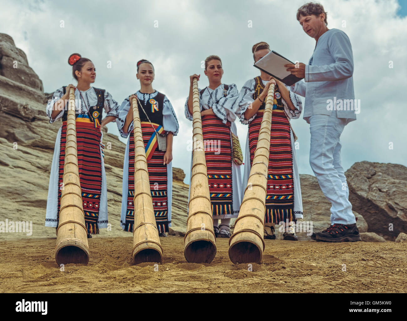 Bucegi Mountains, Romania - August 6, 2016: Romanian female tulnic players in traditional costumes pose near the Sphinx megalith. Stock Photo