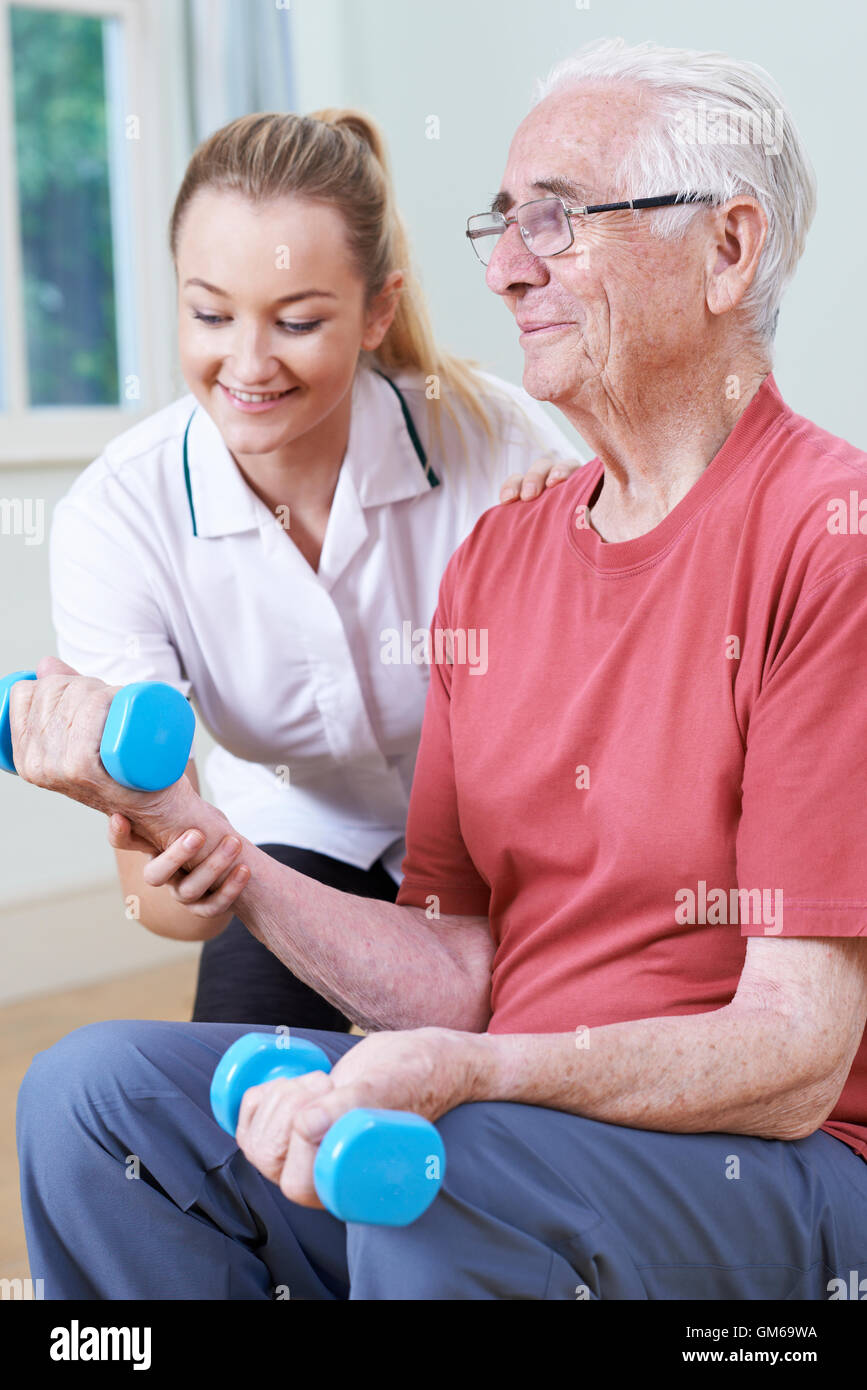 Senior Male Working With Physiotherapist Using Weights Stock Photo