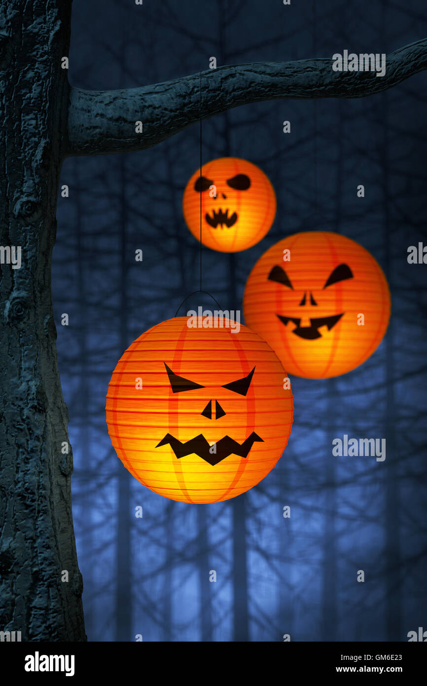 Halloween paper lanterns hanging on a branch in a spooky and foggy forest at night Stock Photo