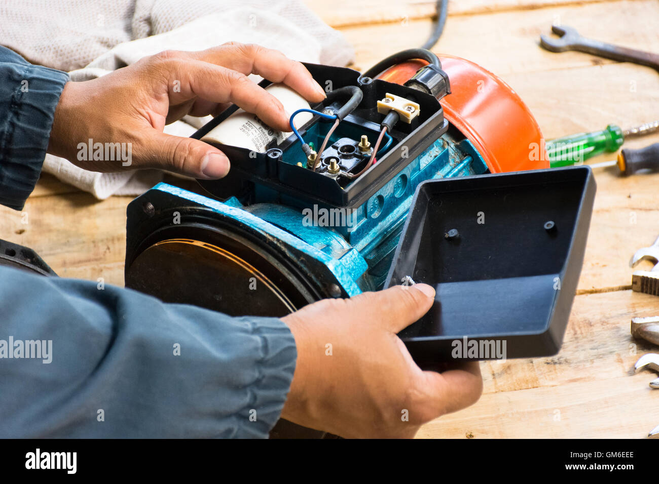 Electric motor and man working equipment repair on wooden floor