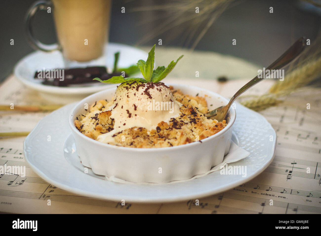 Melting vanilla scoop of ice cream with a mint leave on top of a sweat and crunchy apple pie. Stock Photo