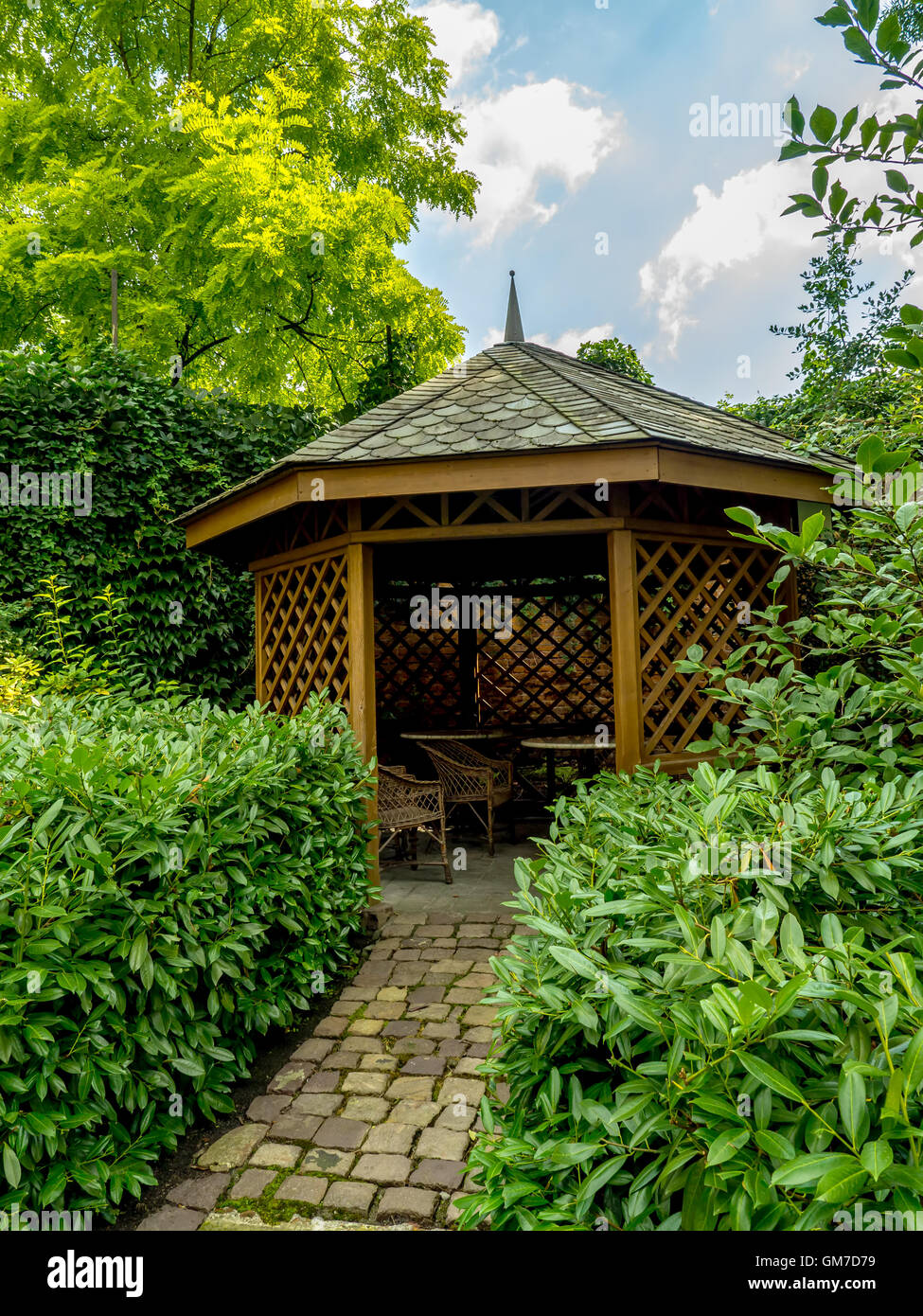 Wooden summer house surrounded by green shrubs and trees Stock Photo