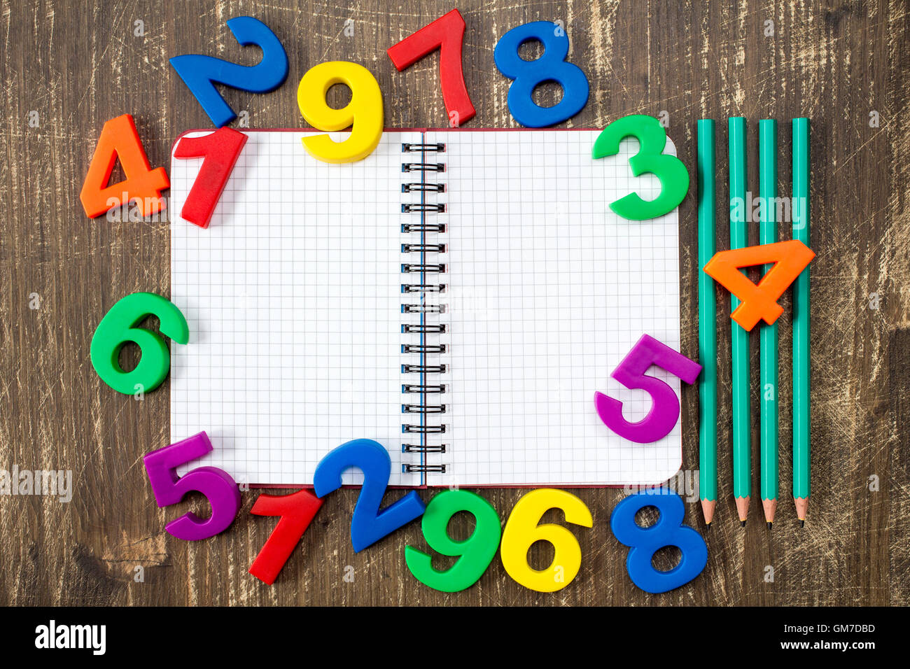 Number In Notebook Open notebook with four pencils and colored numbers on the wood ...