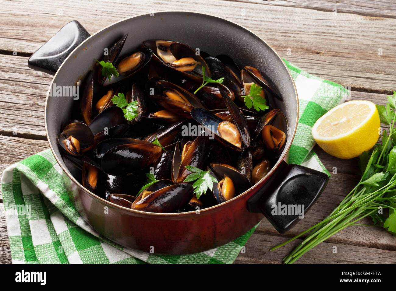 Mussels in copper on wooden table Stock Photo