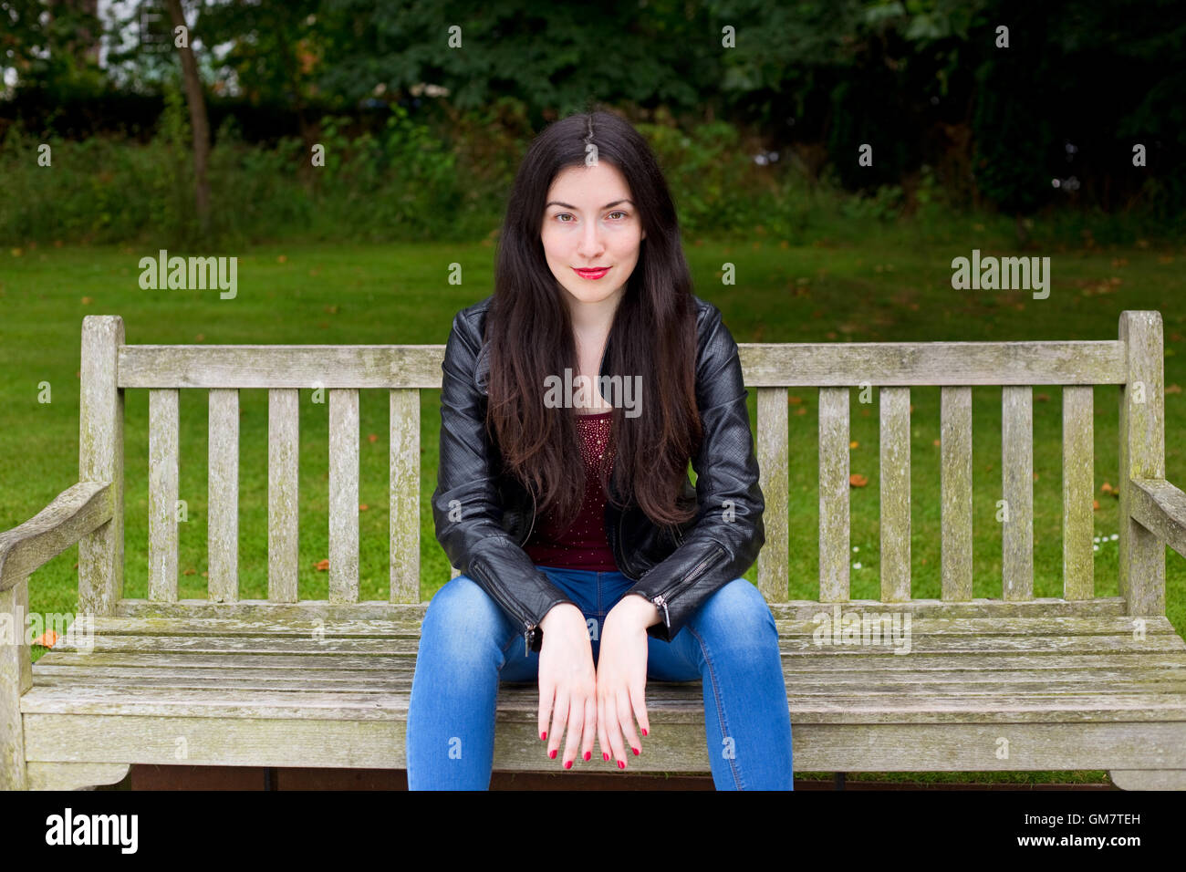 young woman sitting on a park bench Stock Photo - Alamy