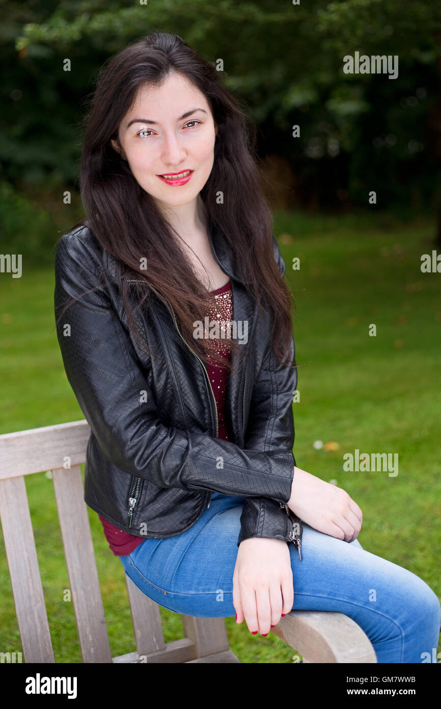 Young woman sitting on a bench in the park Stock Photo