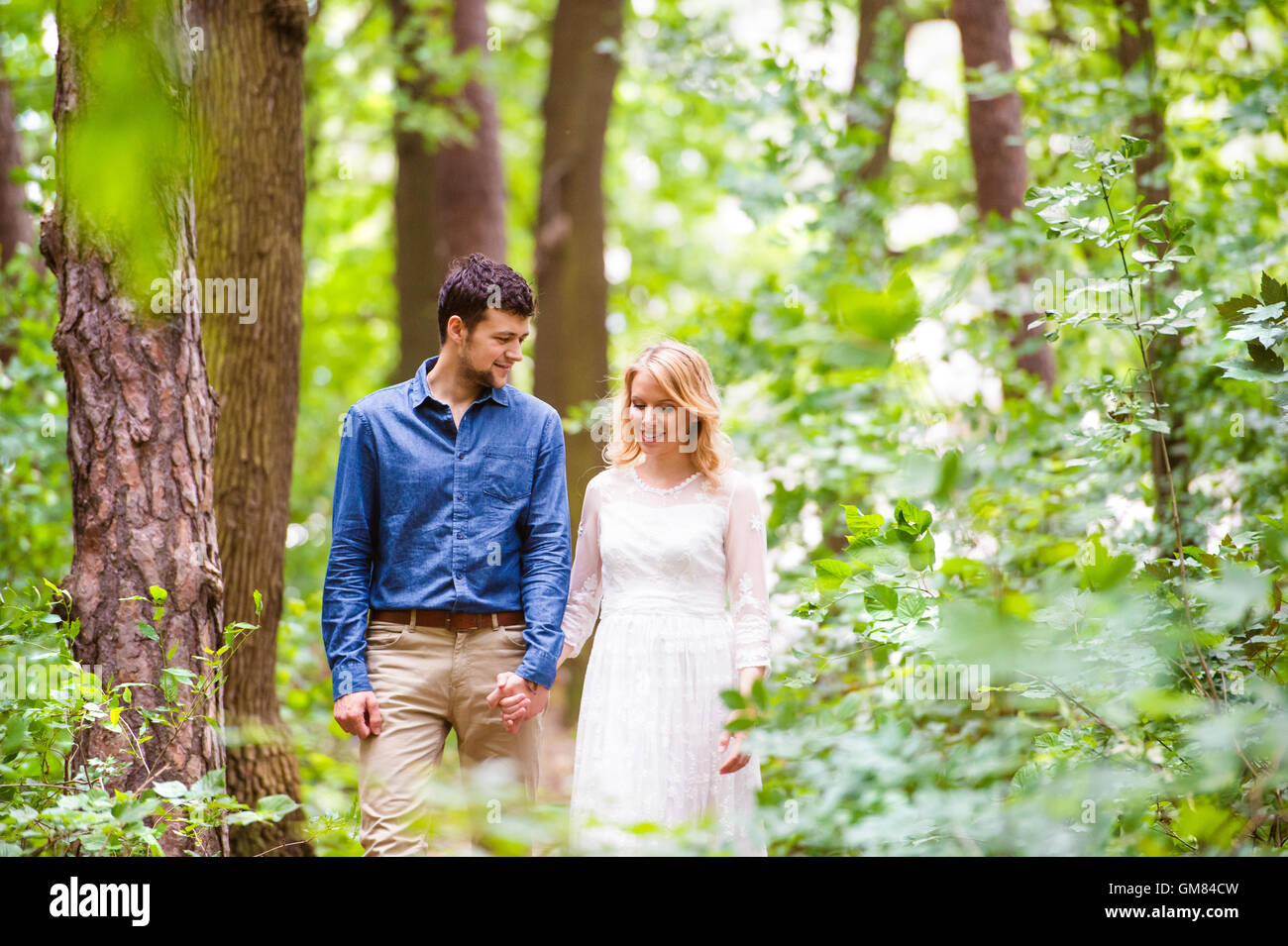 Beautiful wedding couple on a walk in forest, holding hands Stock Photo ...