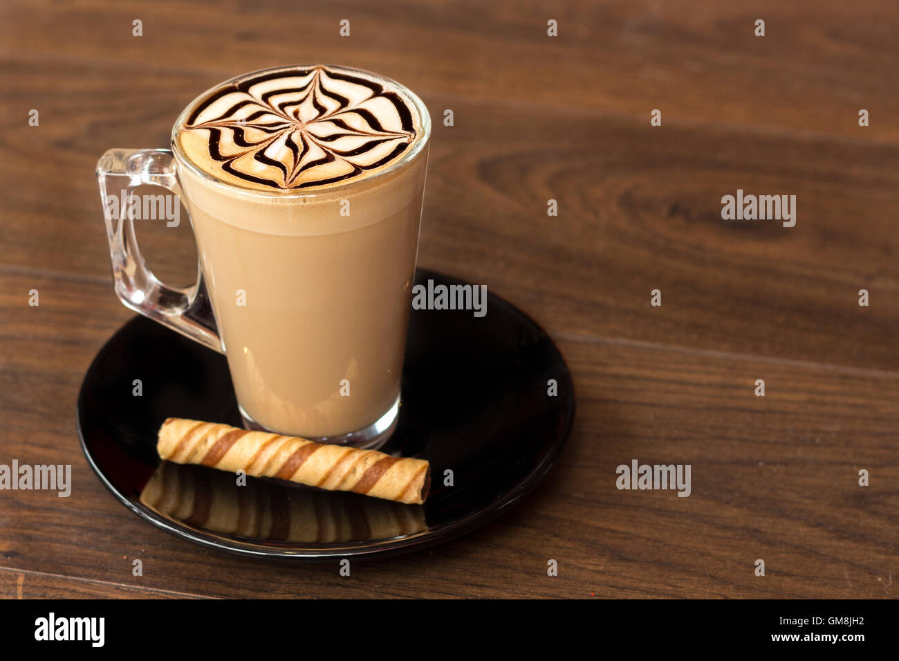 A Latte with some simple latte art on a wood background Stock Photo