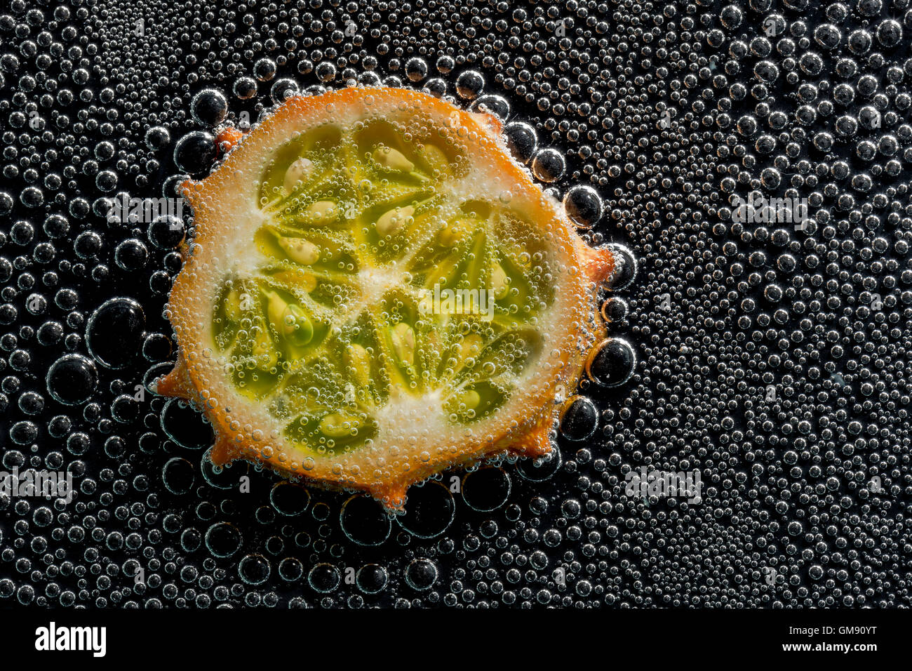Kiwano, horned melon fruit in mineral water, a series of photos. Close-up carbonated water against black background Stock Photo