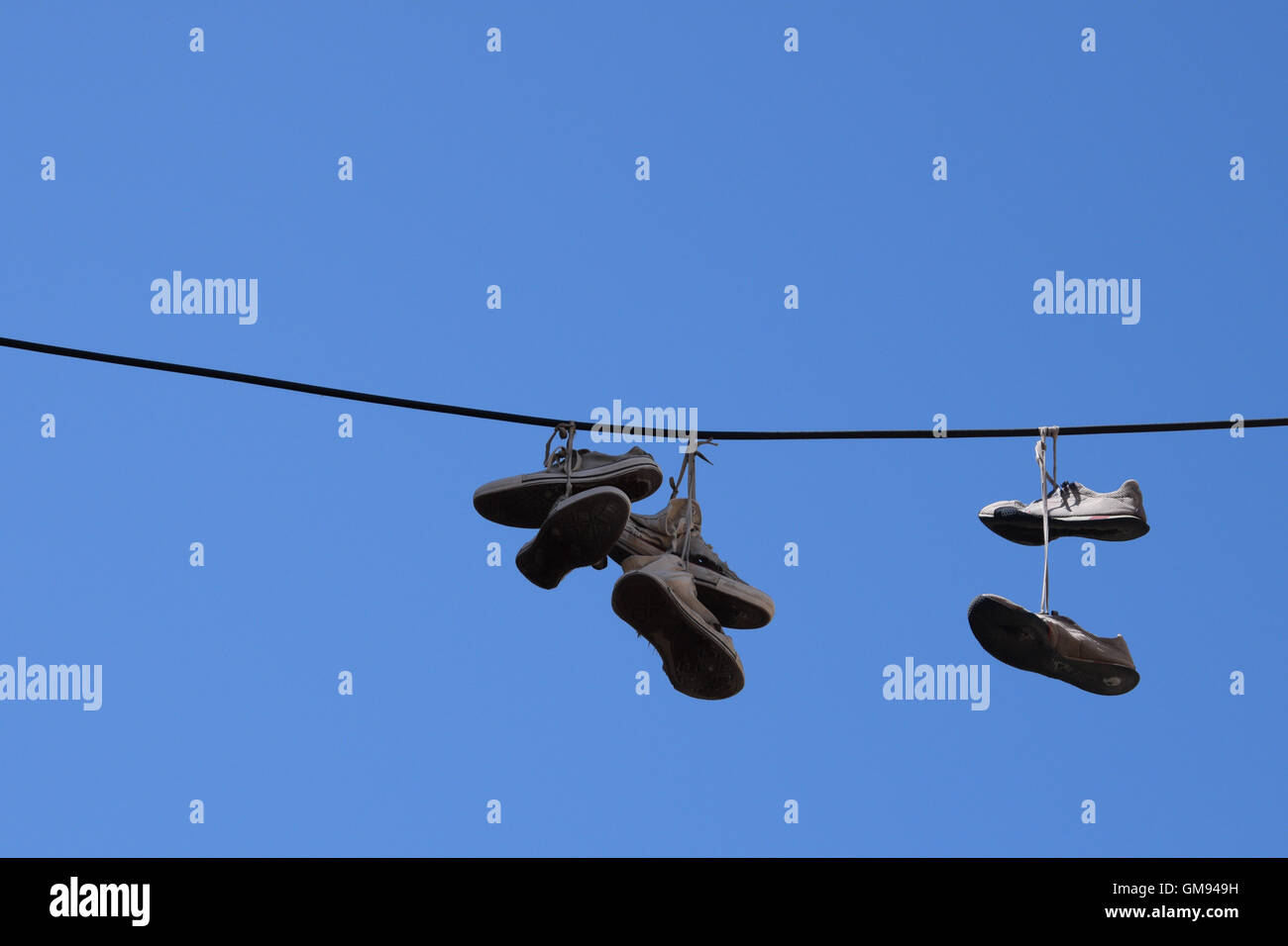 Shoe tossing old sneakers footwear with tied shoelaces hanging from a wire. Stock Photo