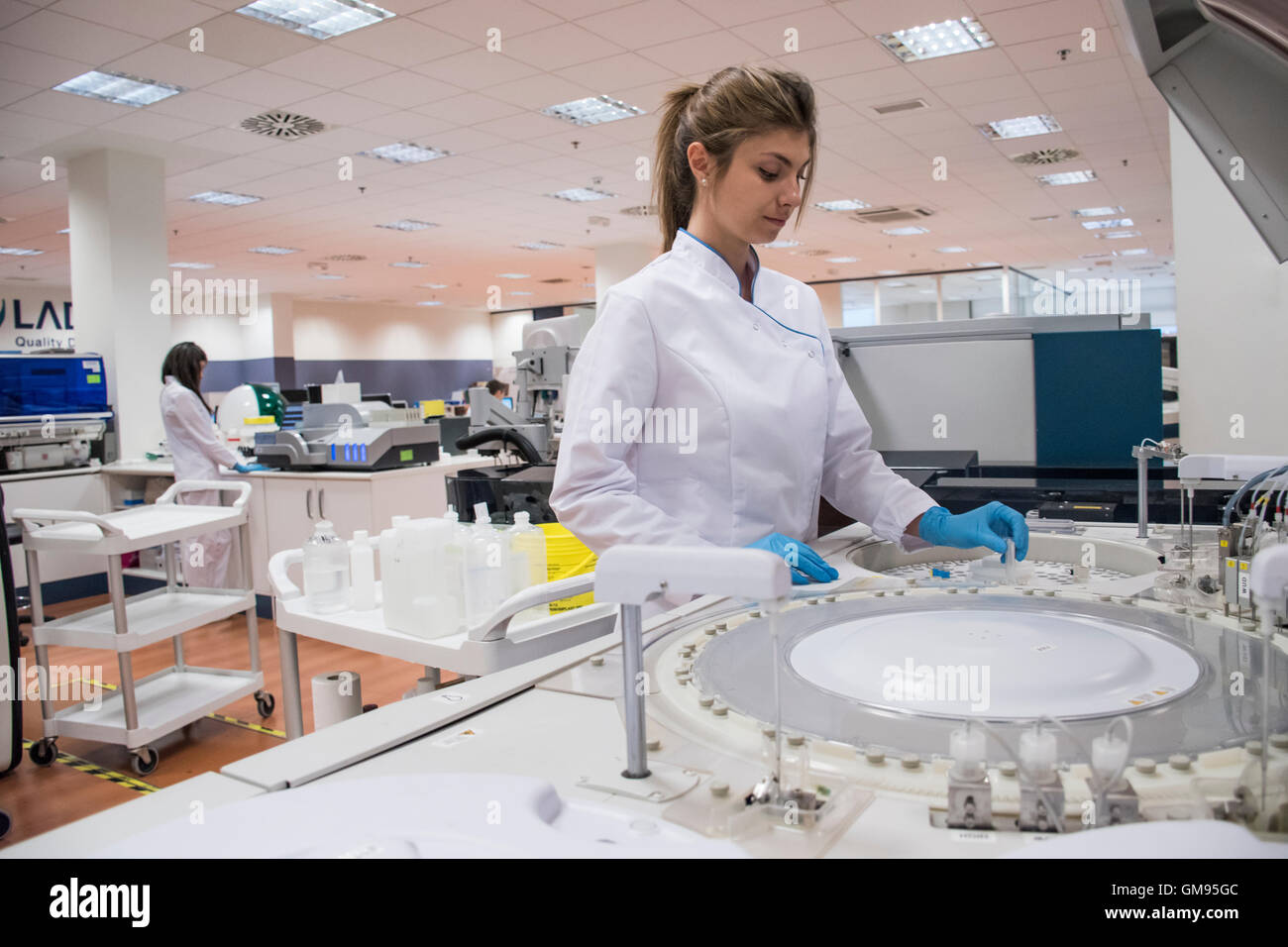 Laboratory technician in analytical laboratory using autoanalyzer Stock