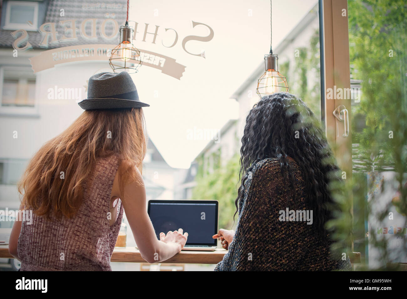 Two young women using laptop in a cafe Stock Photo - Alamy