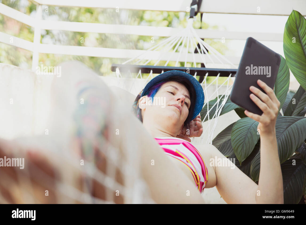 Woman relaxing in a hammock reading e-book Stock Photo - Alamy