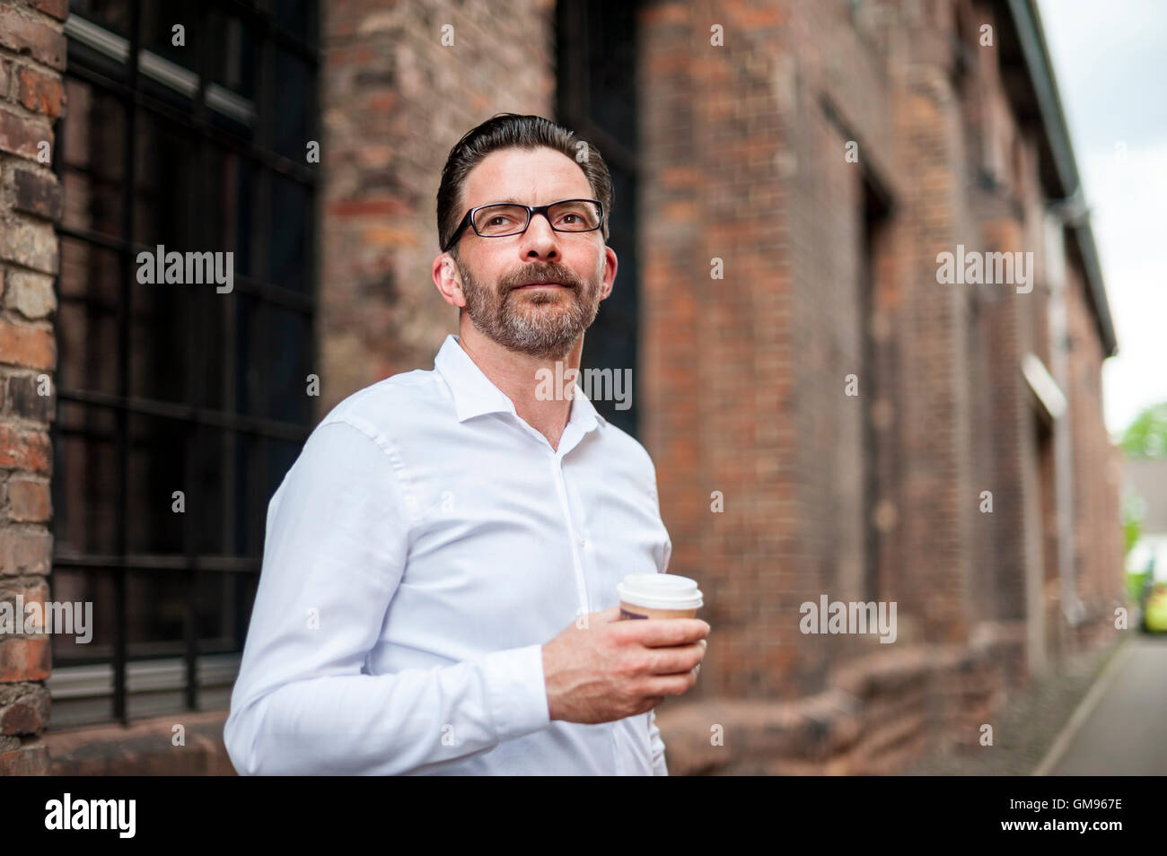 Businessman with coffee to go looking at distance Stock Photo