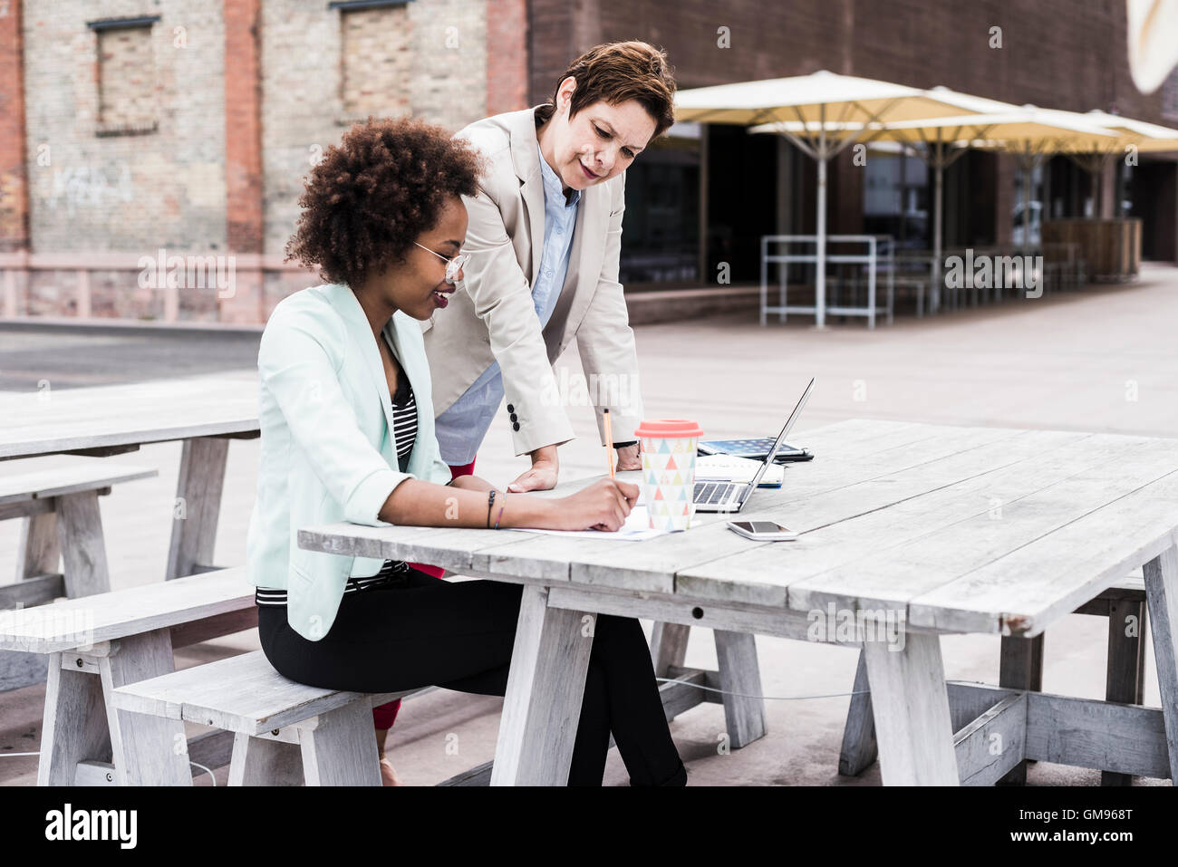 Two businesswomen working on terrace of a pavement cafe Stock Photo - Alamy