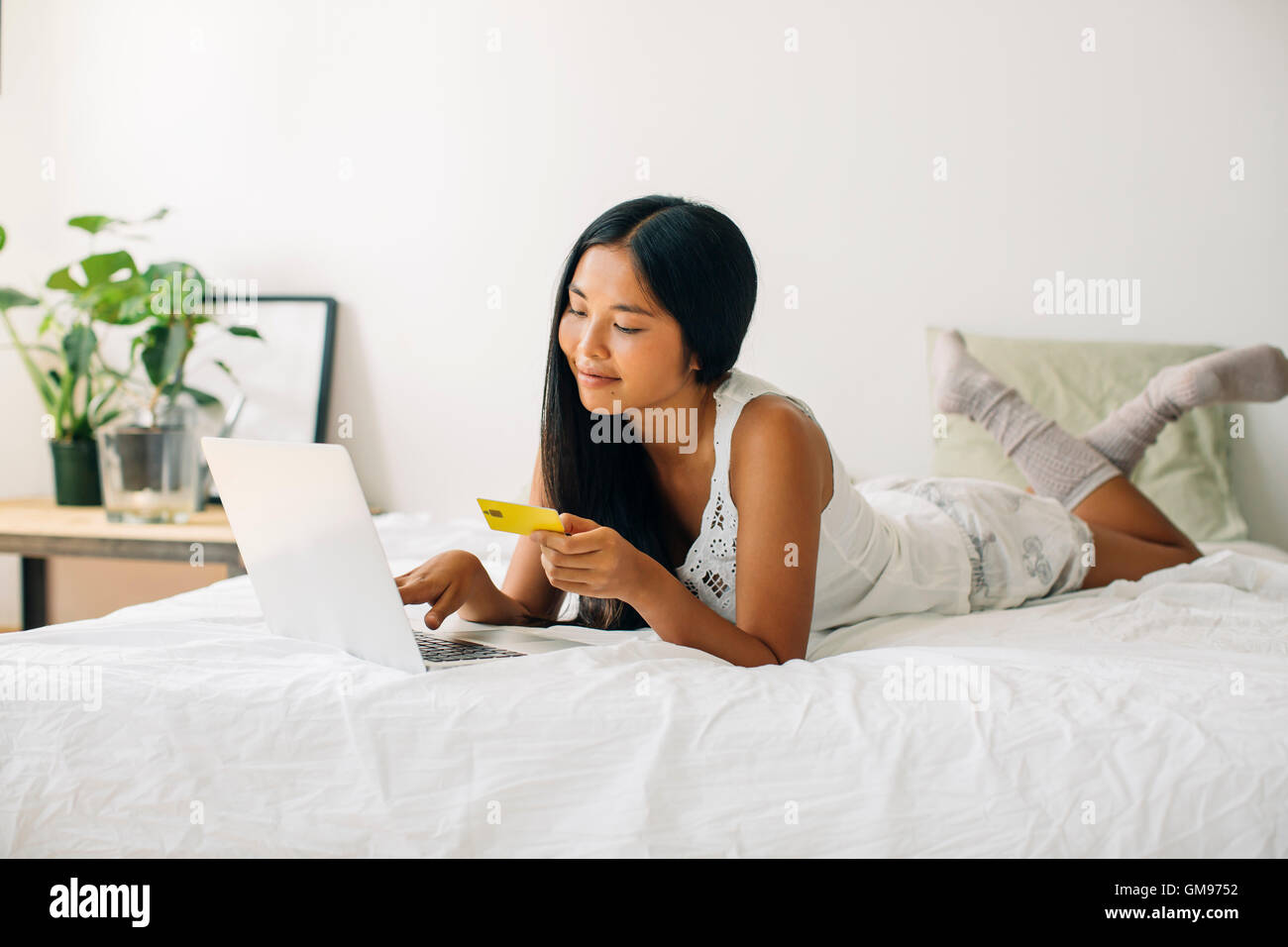 Young woman lying in bed shopping online Stock Photo Alamy