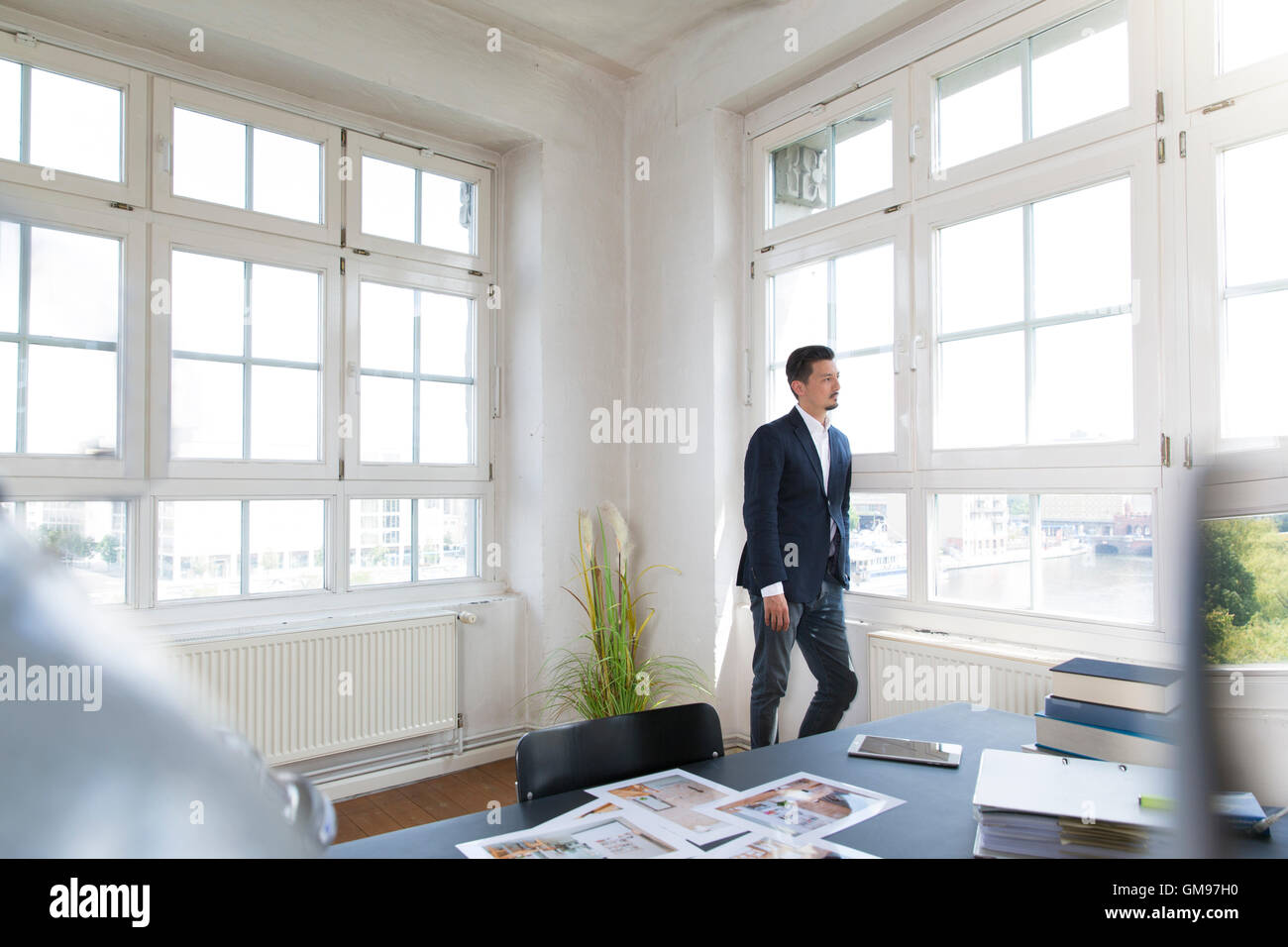 Businessman standing at the window with arms crossed Stock Photo - Alamy