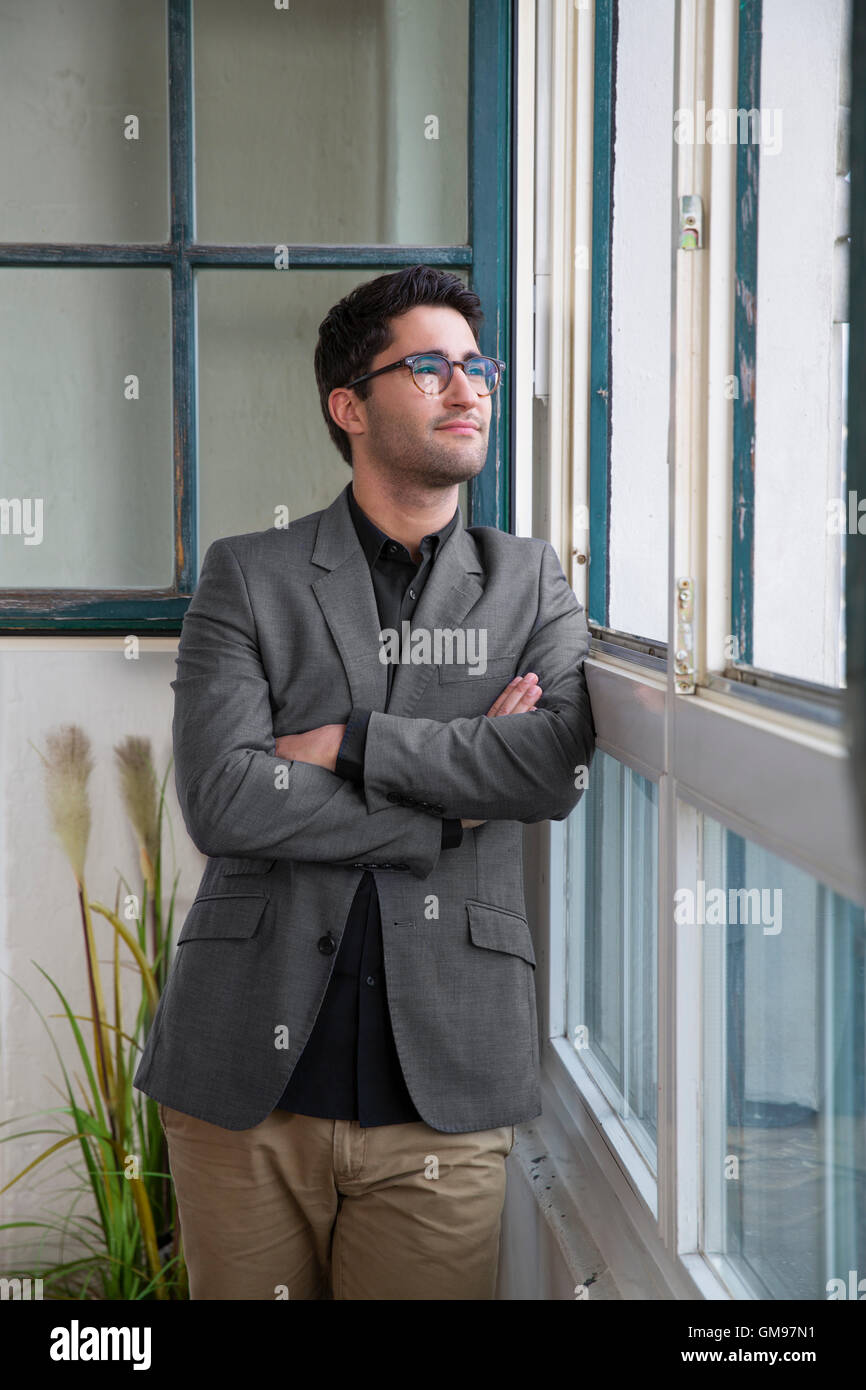 Businessman standing at the window with arms crossed Stock Photo - Alamy