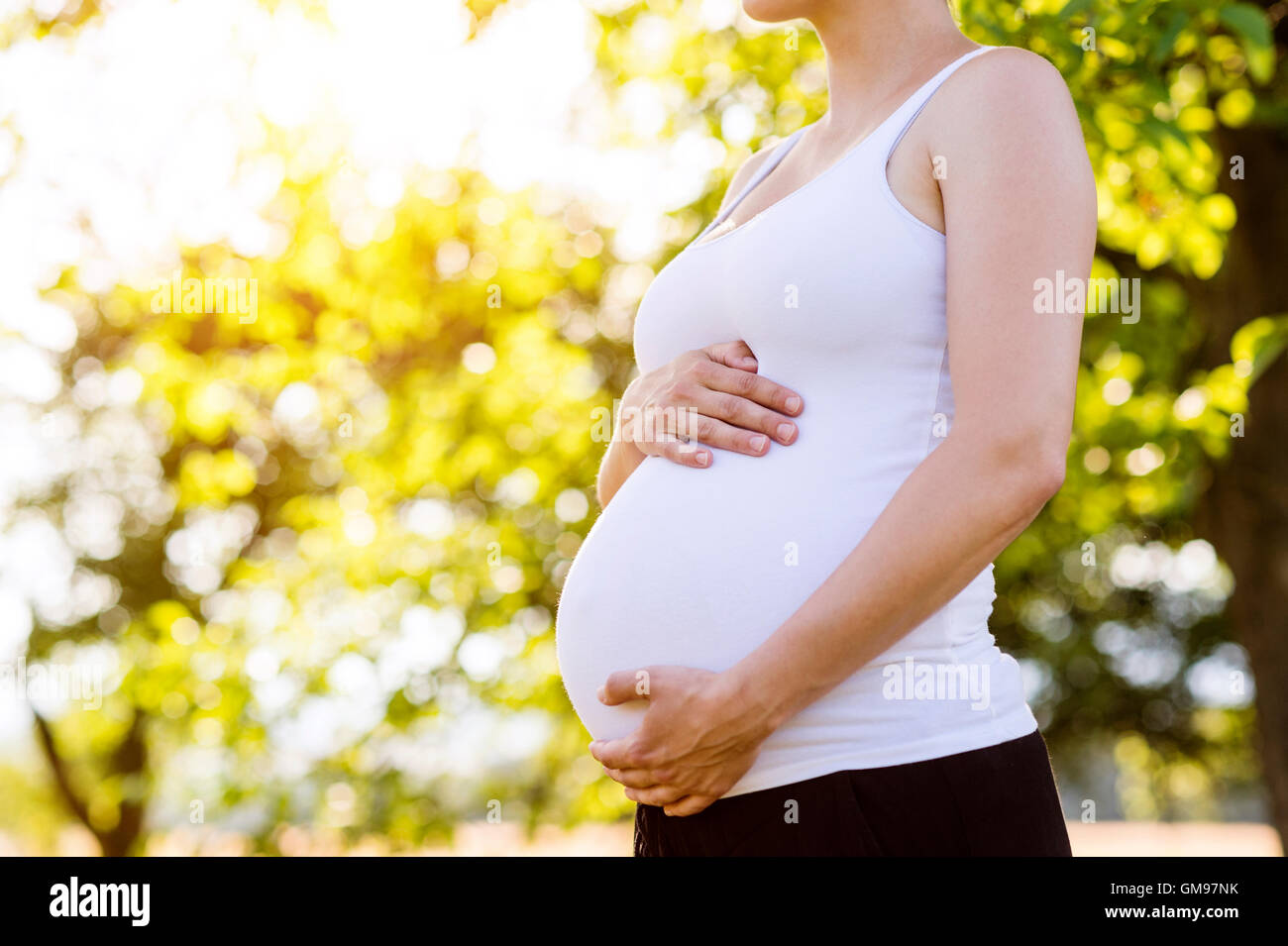 Pregnant woman holding belly, standing in nature Stock Photo Alamy