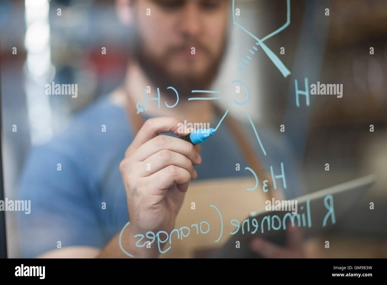 Man writing formula on glass pane Stock Photo - Alamy