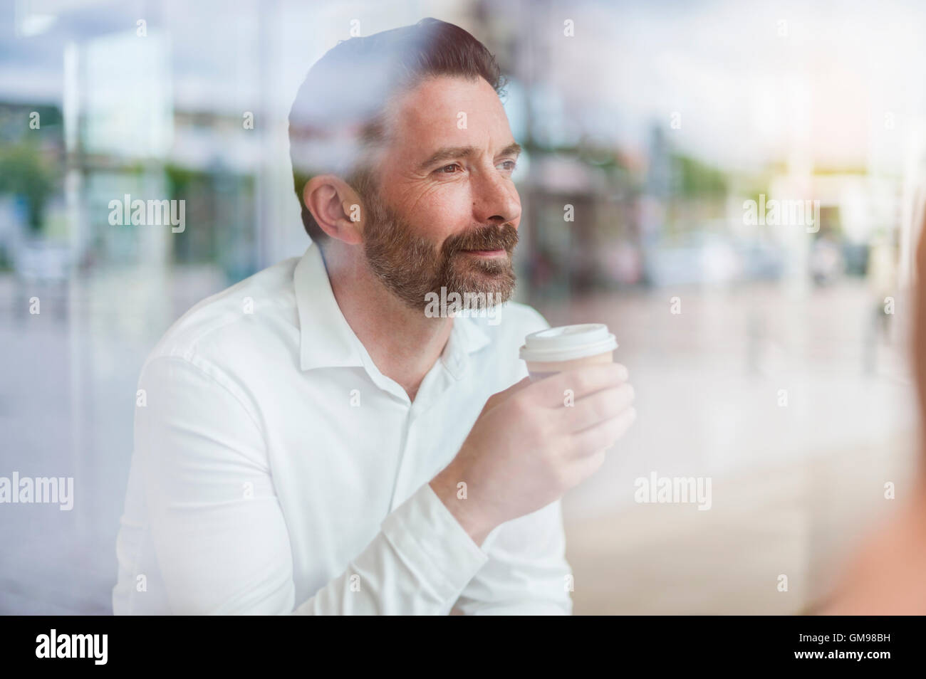 Portrait of relaxed businessman looking through window of coffee shop Stock Photo