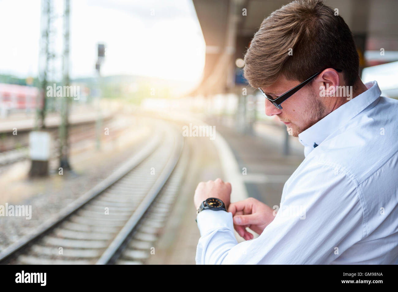 Young man at station platform checking the time Stock Photo