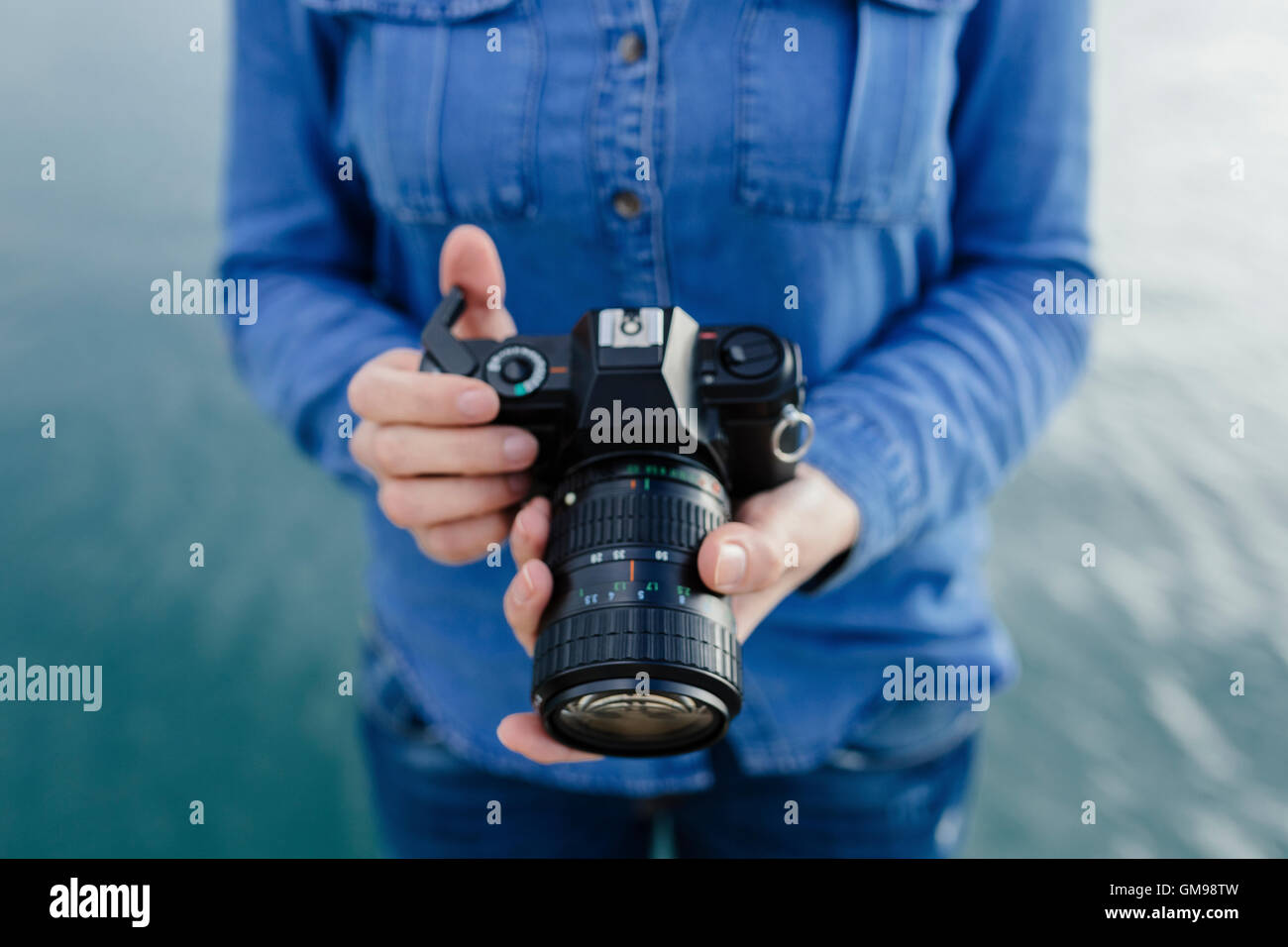 Young woman at the waterfront holding camera Stock Photo - Alamy