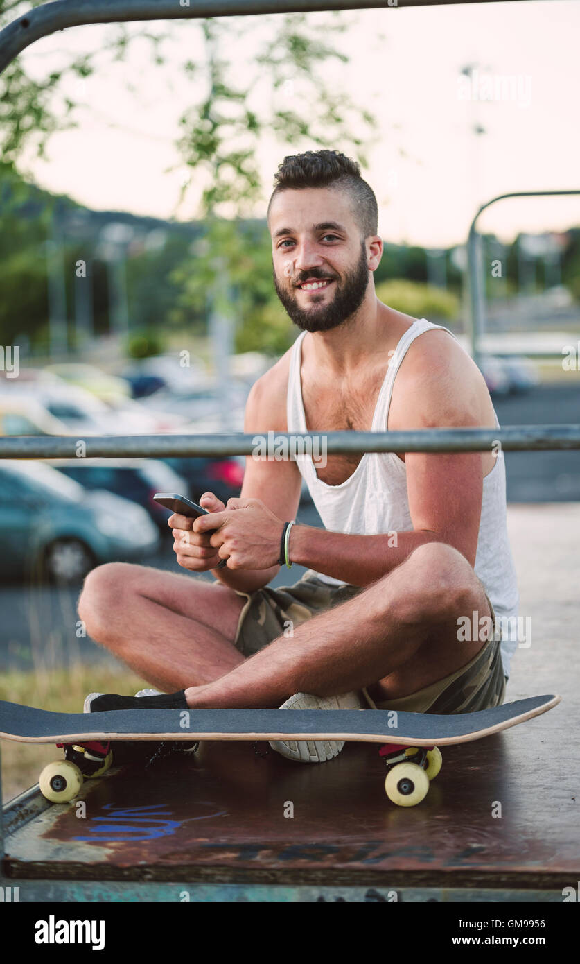Portrait of smiling skateboarder with   smartphone Stock Photo