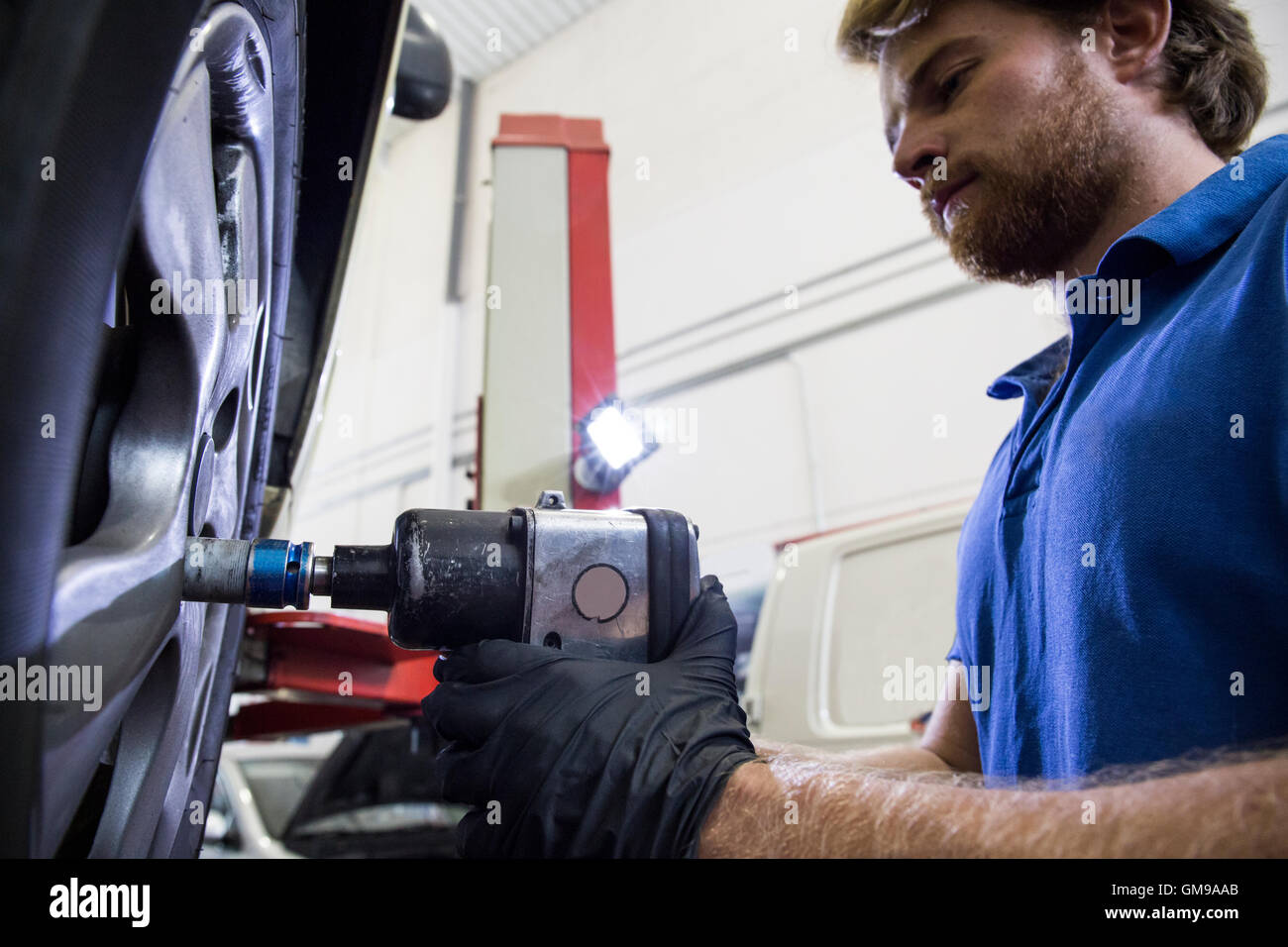 Mechanic fixing a car wheel in a workshop Stock Photo - Alamy