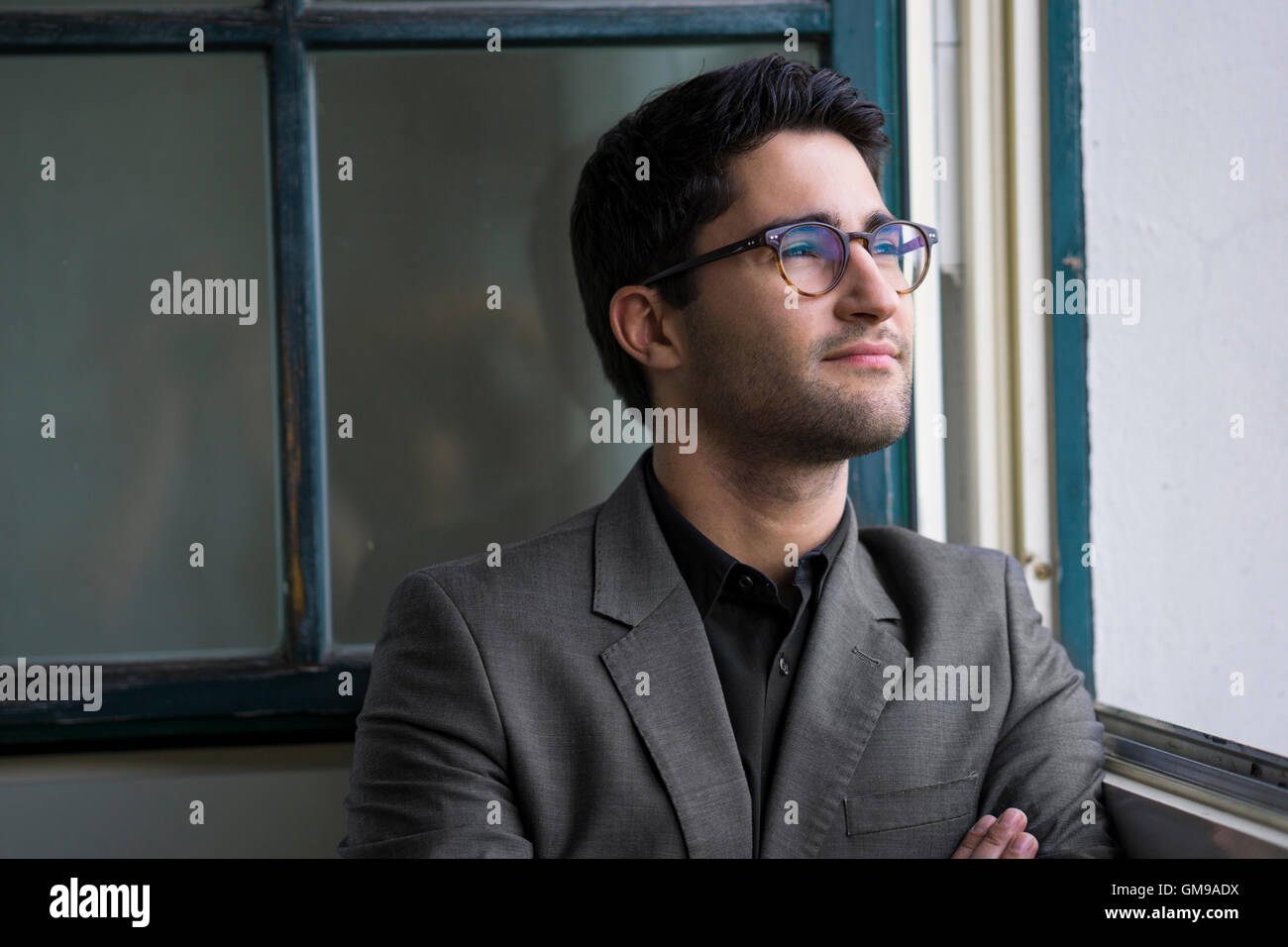 Businessman standing at the window with arms crossed Stock Photo - Alamy