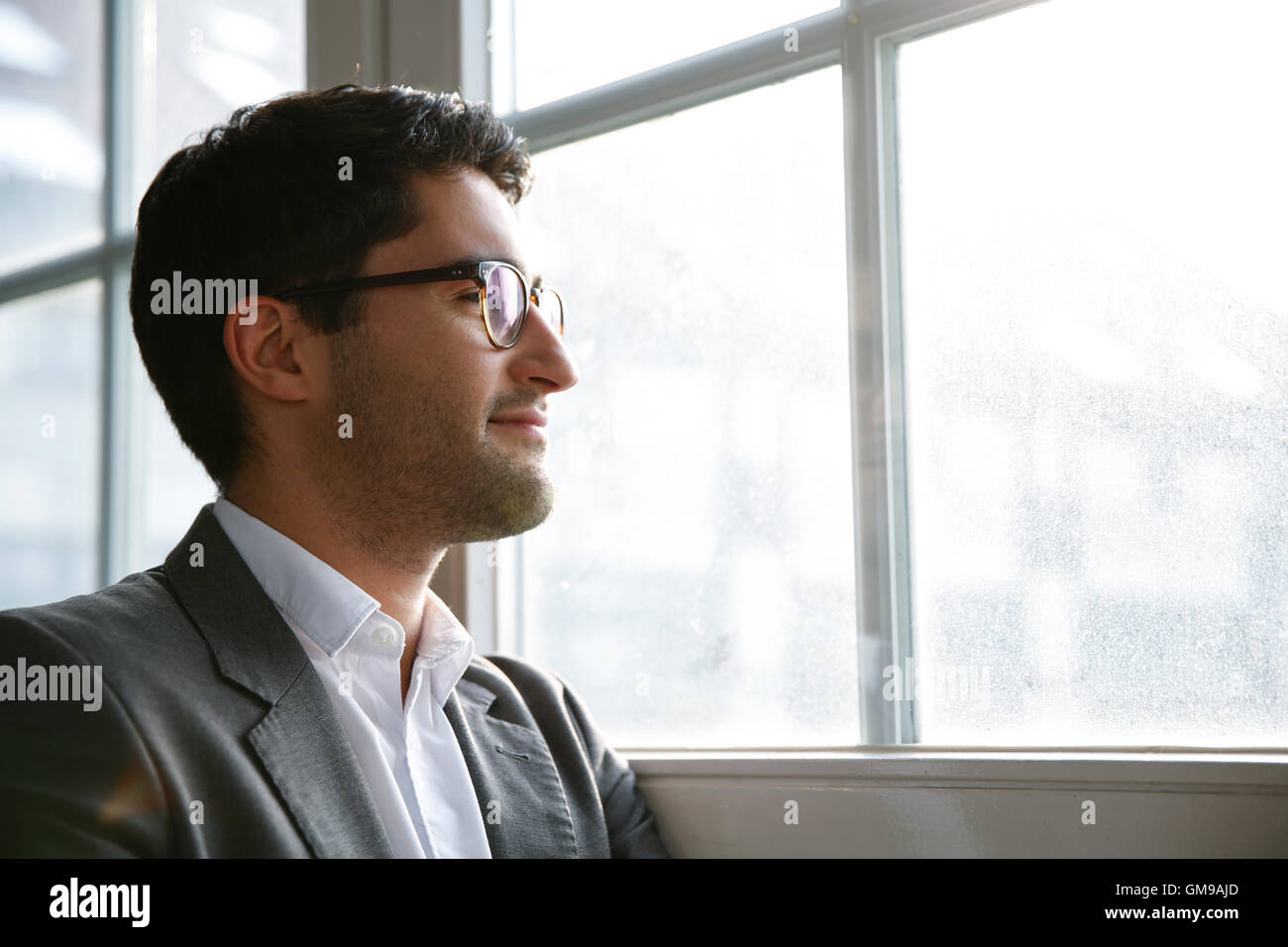 Businessman standing at the window with arms crossed Stock Photo - Alamy
