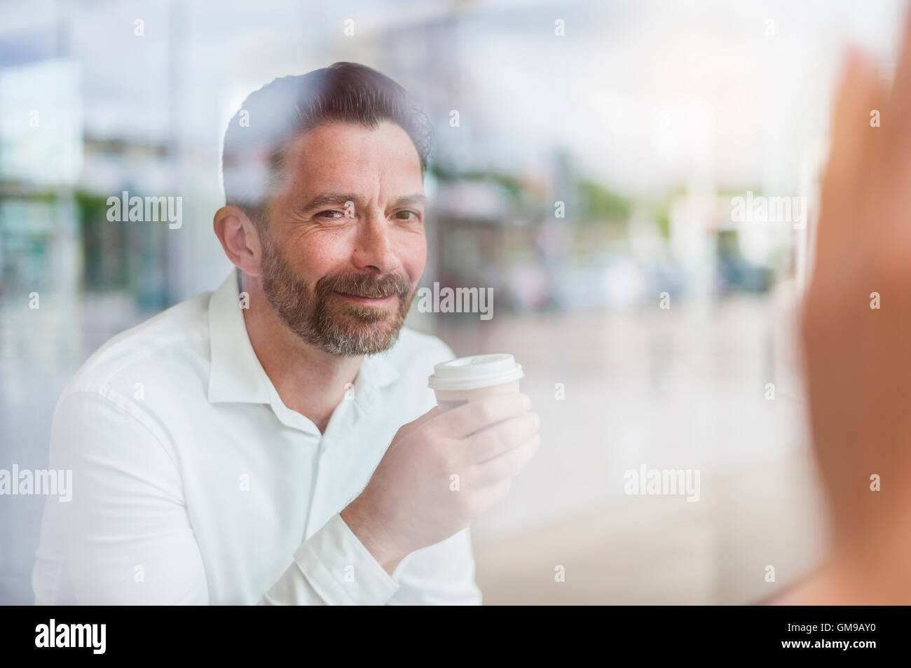 Portrait of smiling businessman in a coffee shop looking through window Stock Photo