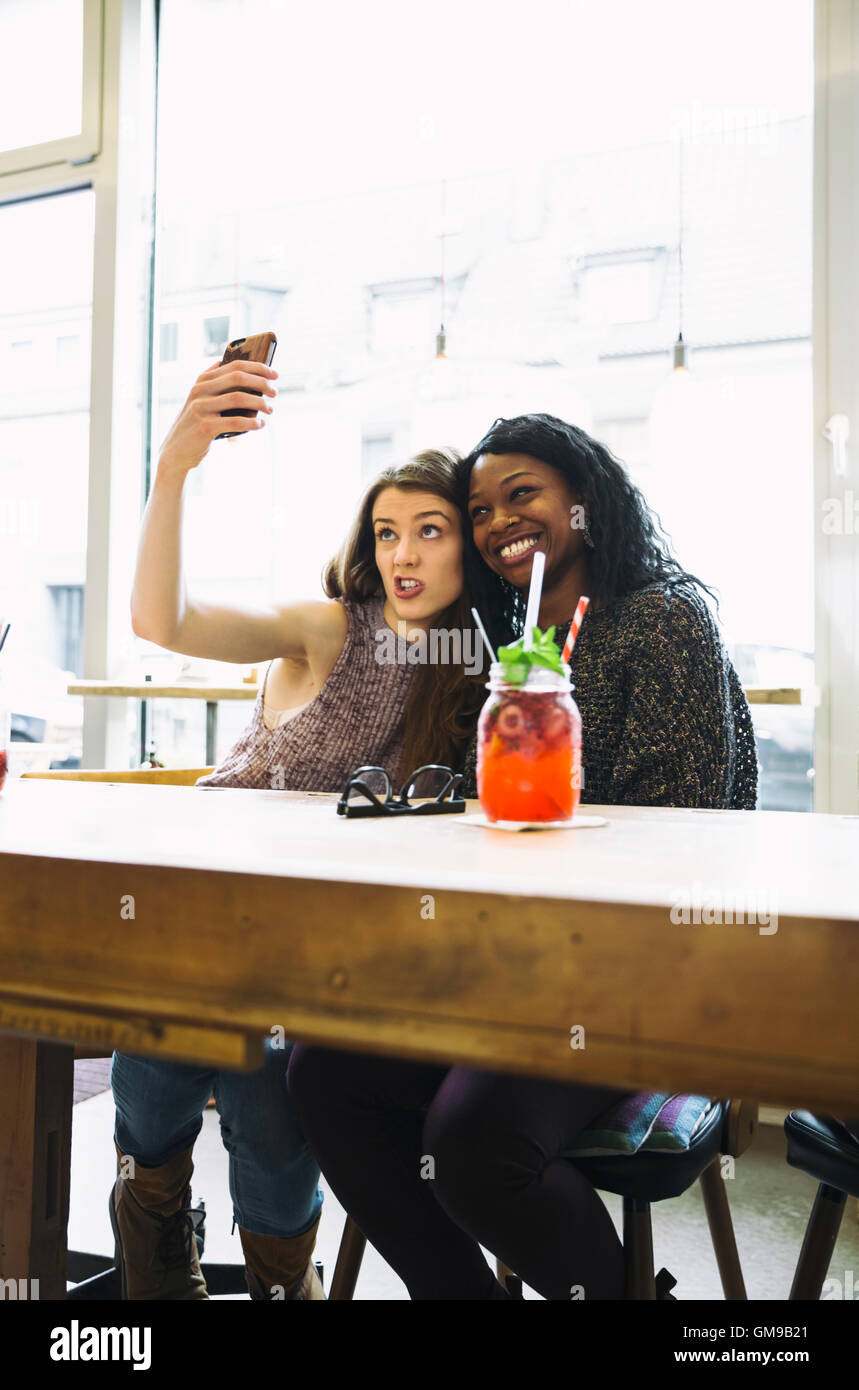 Two young women taking selfie in a cafe Stock Photo - Alamy