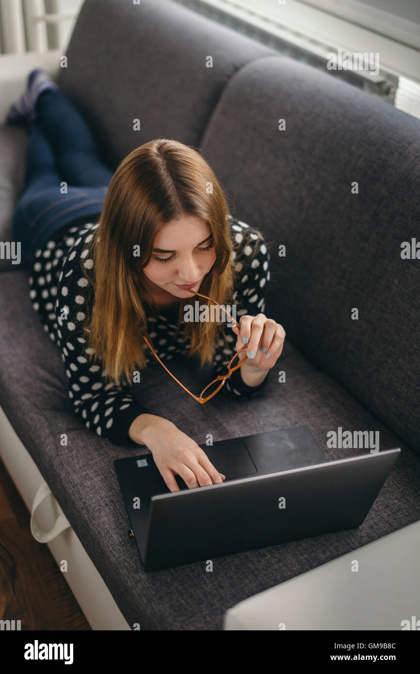 Young woman relaxing on the couch using laptop Stock Photo - Alamy