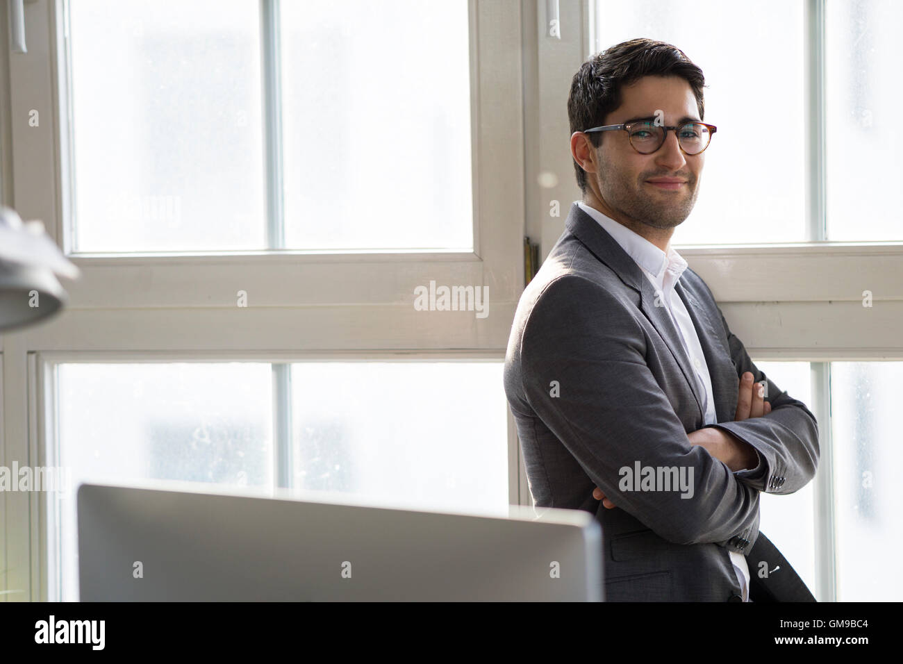 Businessman standing at the window with arms crossed Stock Photo - Alamy