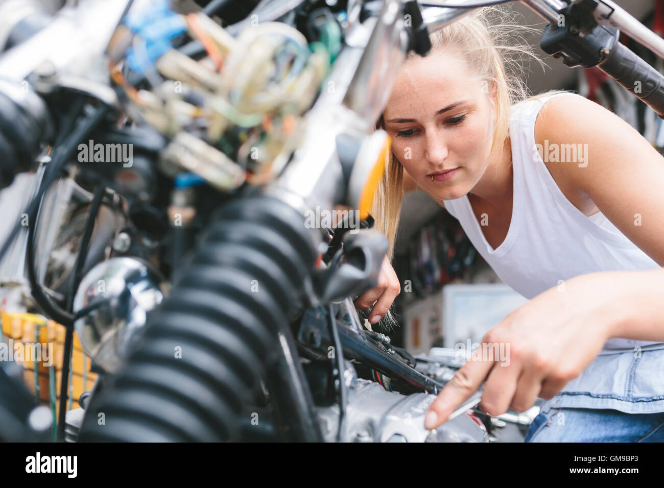 Young woman examining motorbike Stock Photo