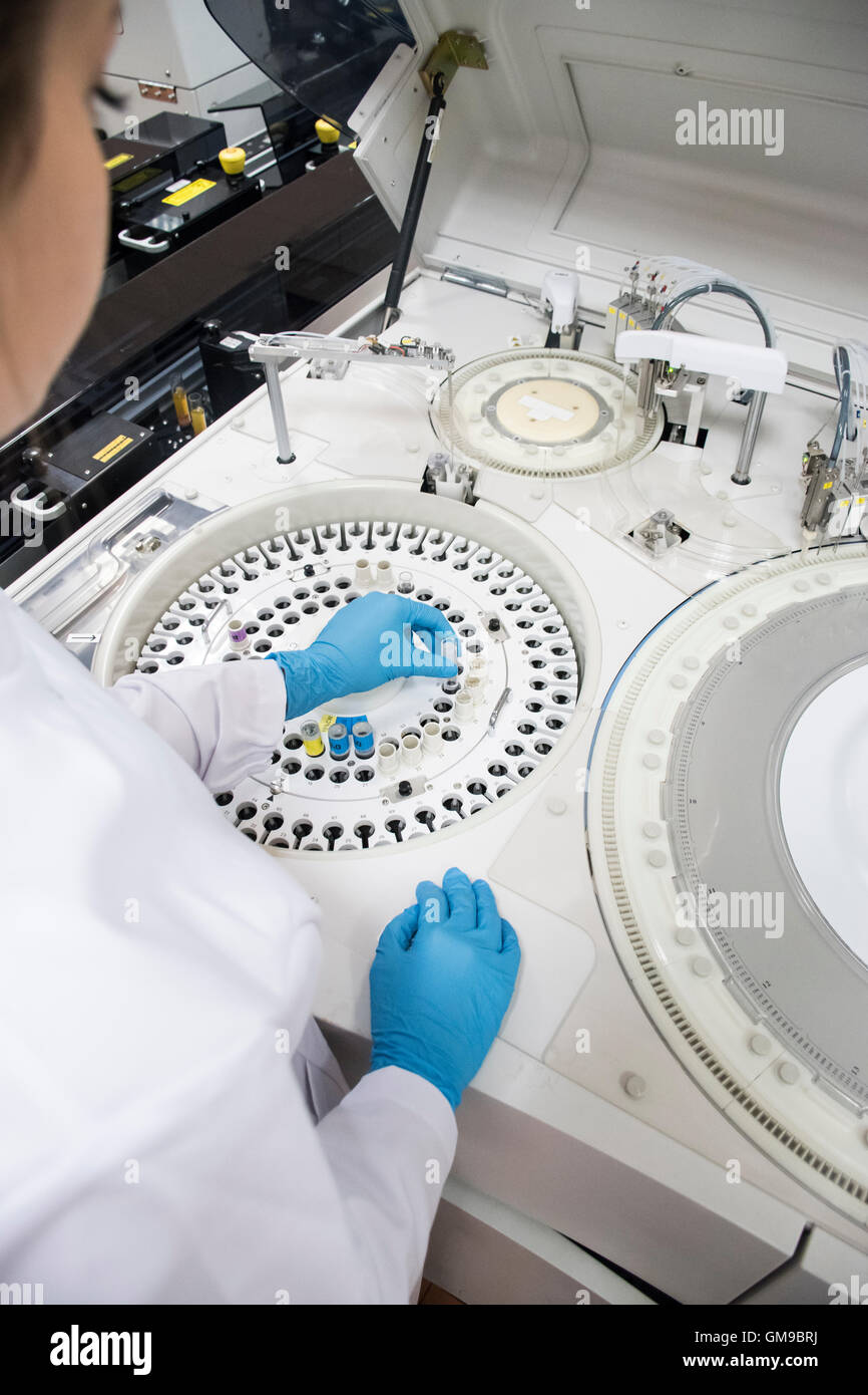 Laboratory technician in analytical laboratory using autoanalyzer Stock