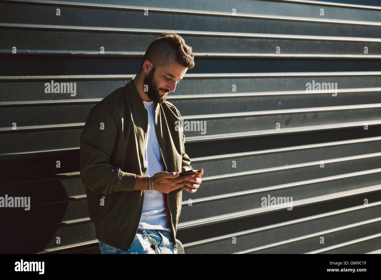 Smiling man standing in front of facade lookiung at cell phone Stock ...