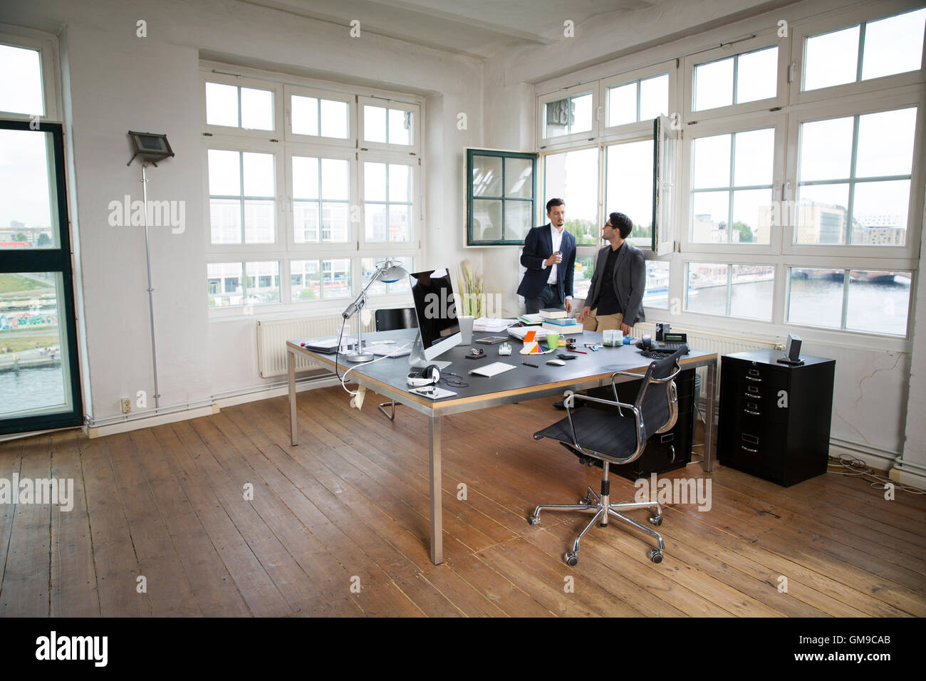 Two businessman standing at the window, talking Stock Photo - Alamy