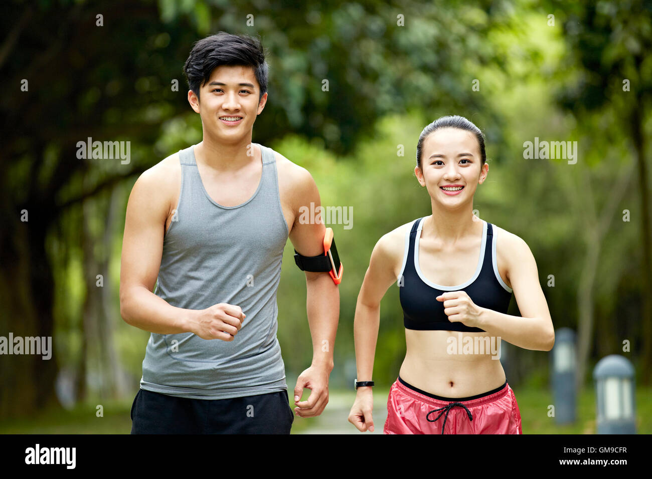 young asian man and woman couple running jogging in a city park. Stock Photo