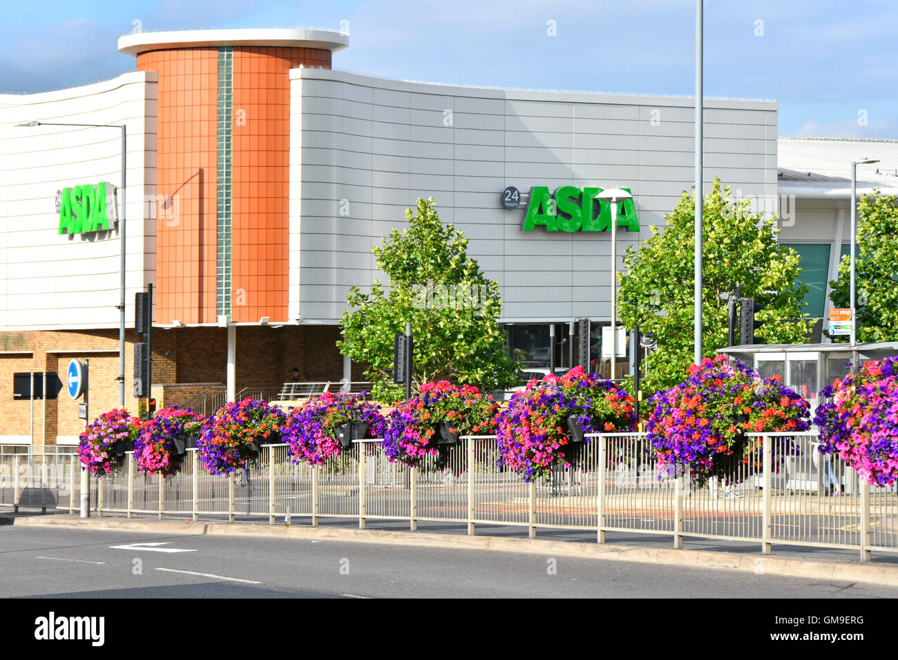 Twenty four hour Asda Supermarket shopping centre in Rugby town centre with summer flower displays along dual carriageway Warwickshire England UK Stock Photo