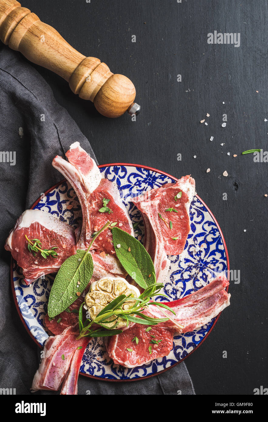 Raw uncooked lamb chops with herbs and spices on colorful plate over
