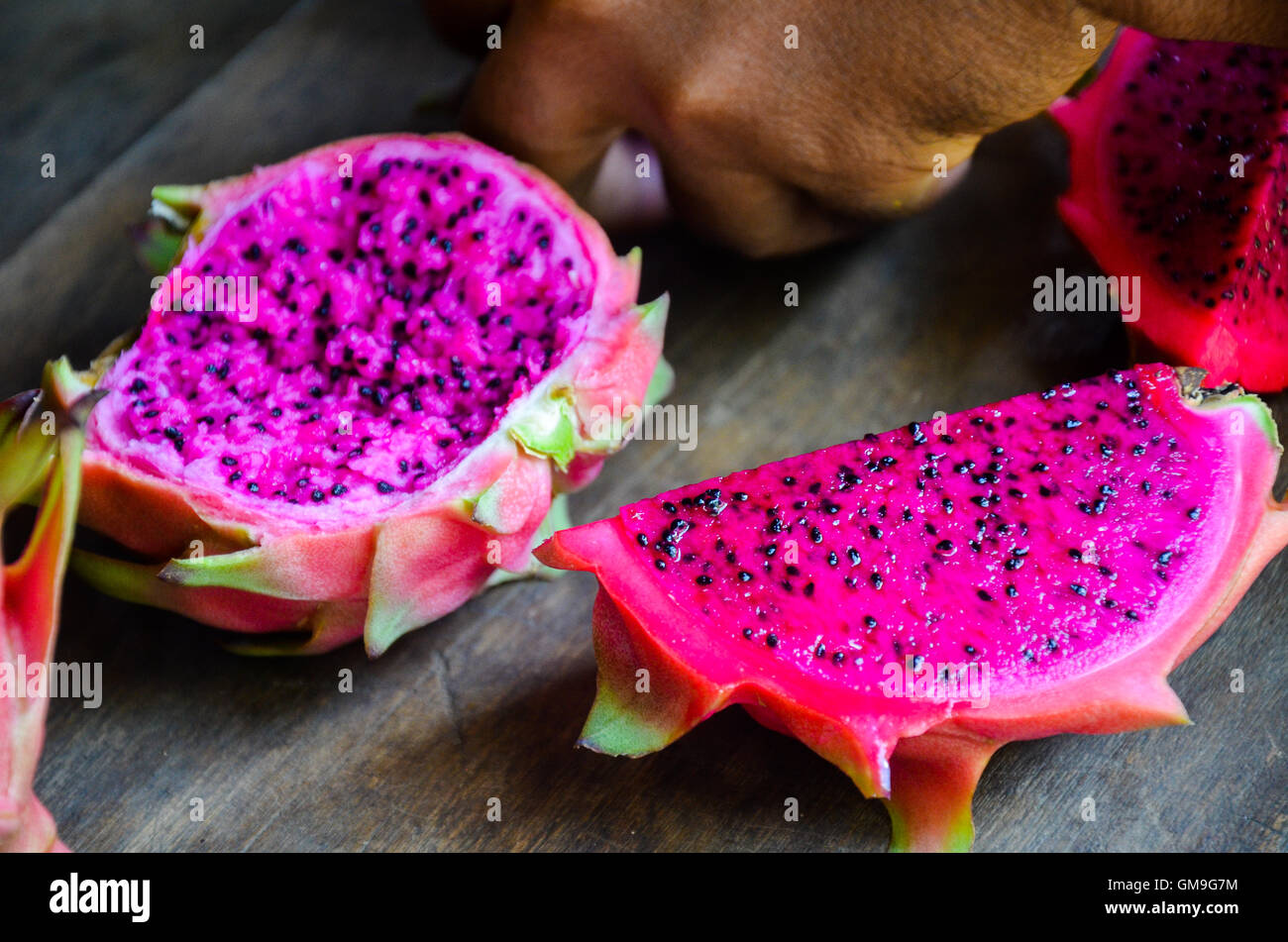 Vivid and vibrant red dragon fruit cut on old wooden table, Chi Phat