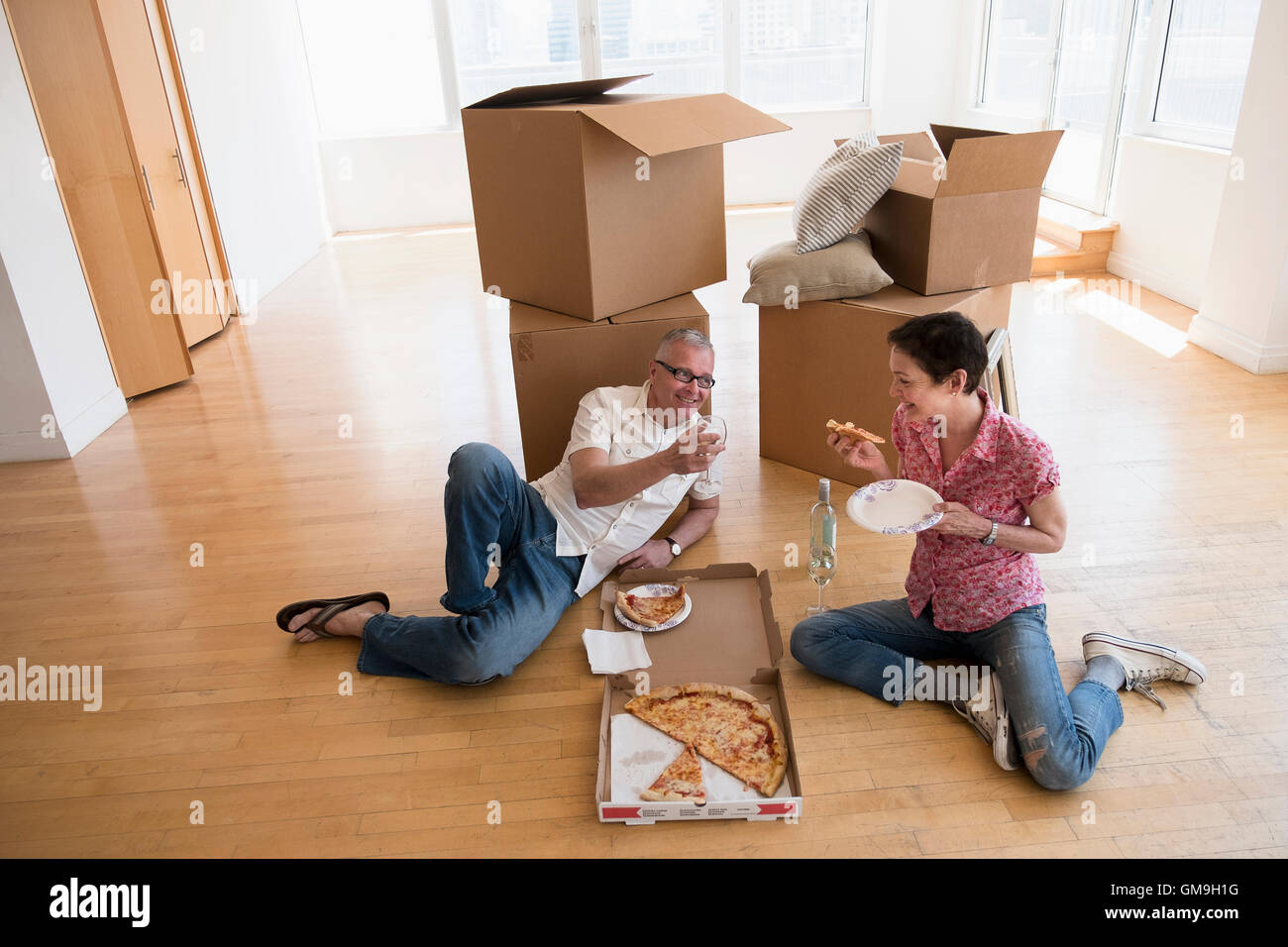 Couple eating pizza in new apartment Stock Photo