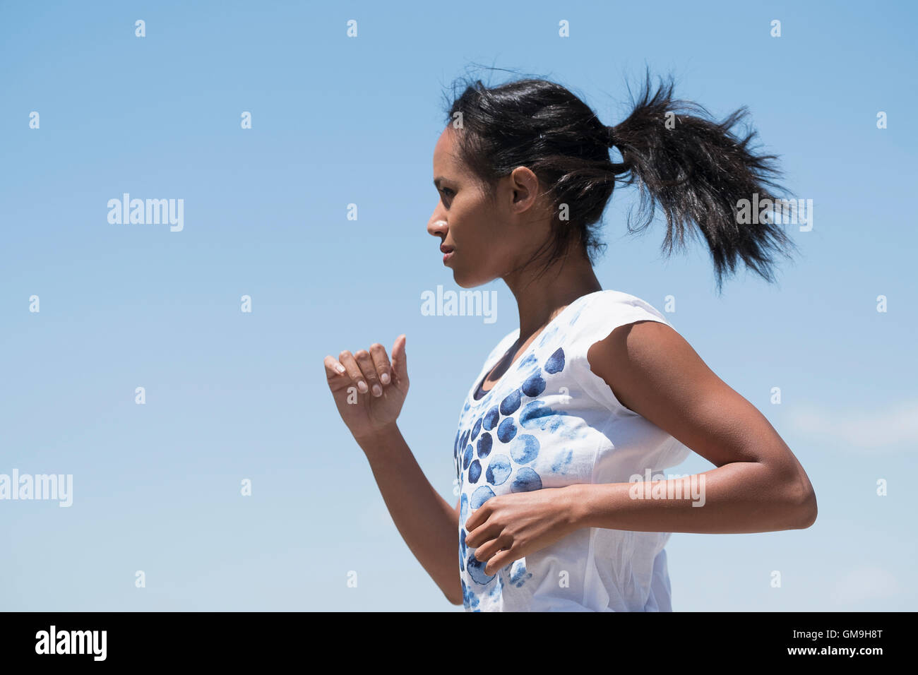 Profile of woman jogging against sky Stock Photo