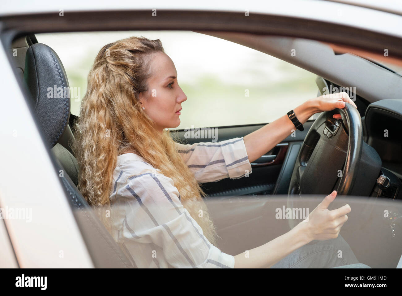 Woman with curly, long, blond hair driving car Stock Photo