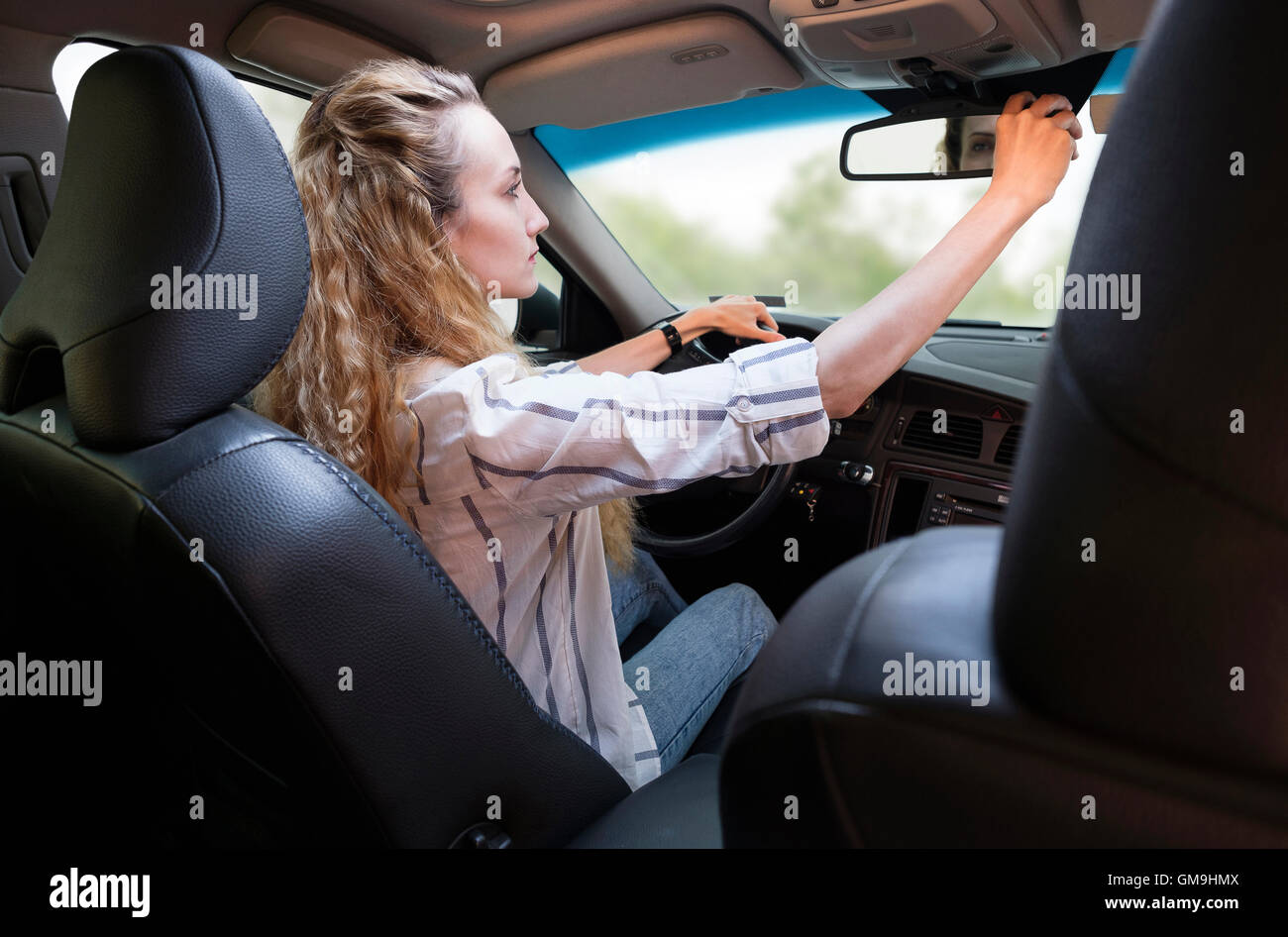 Woman adjusting rear-view mirror during driving car Stock Photo